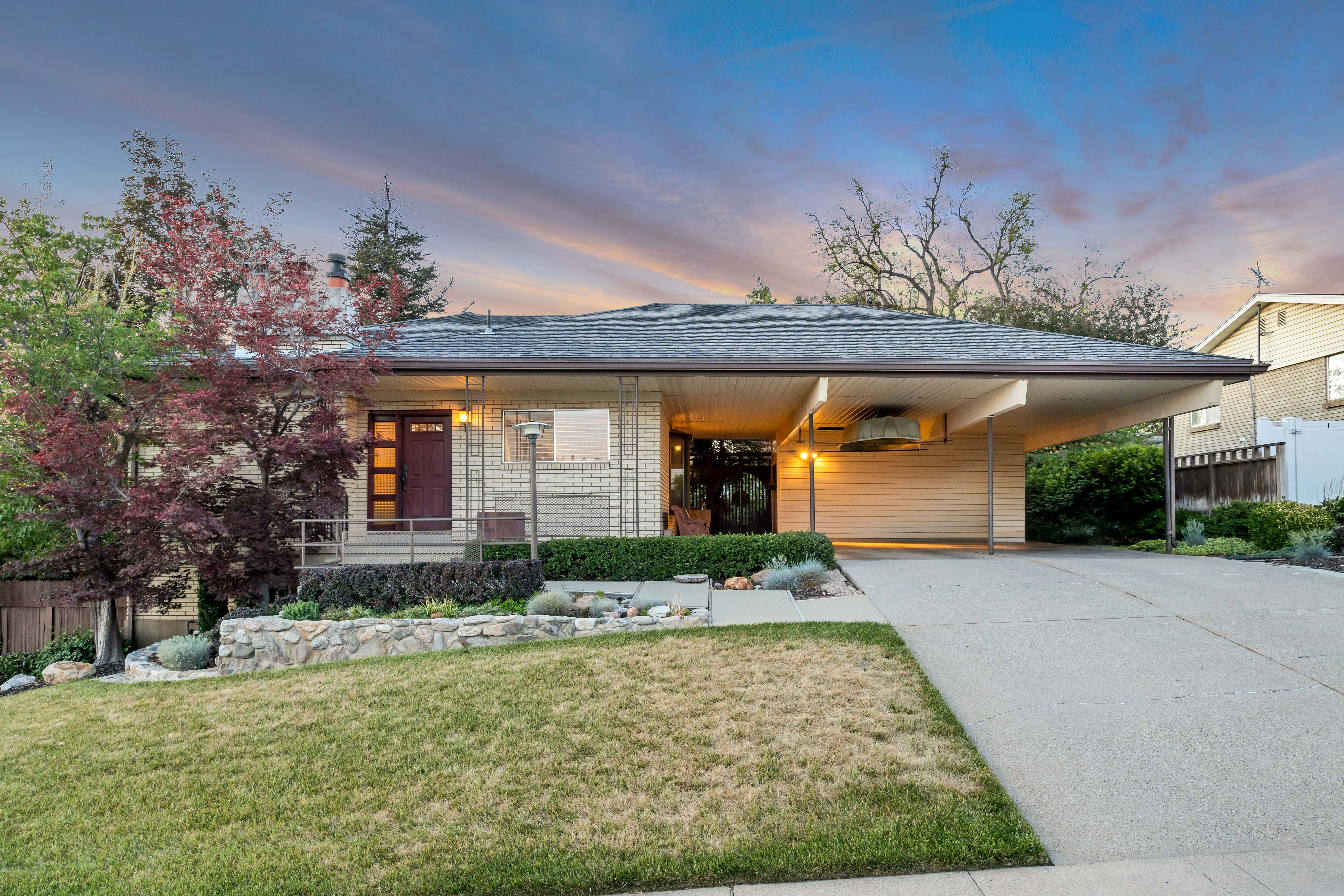 Contemporary single-story residence featuring a covered carport, a concrete driveway, and a manicured front lawn