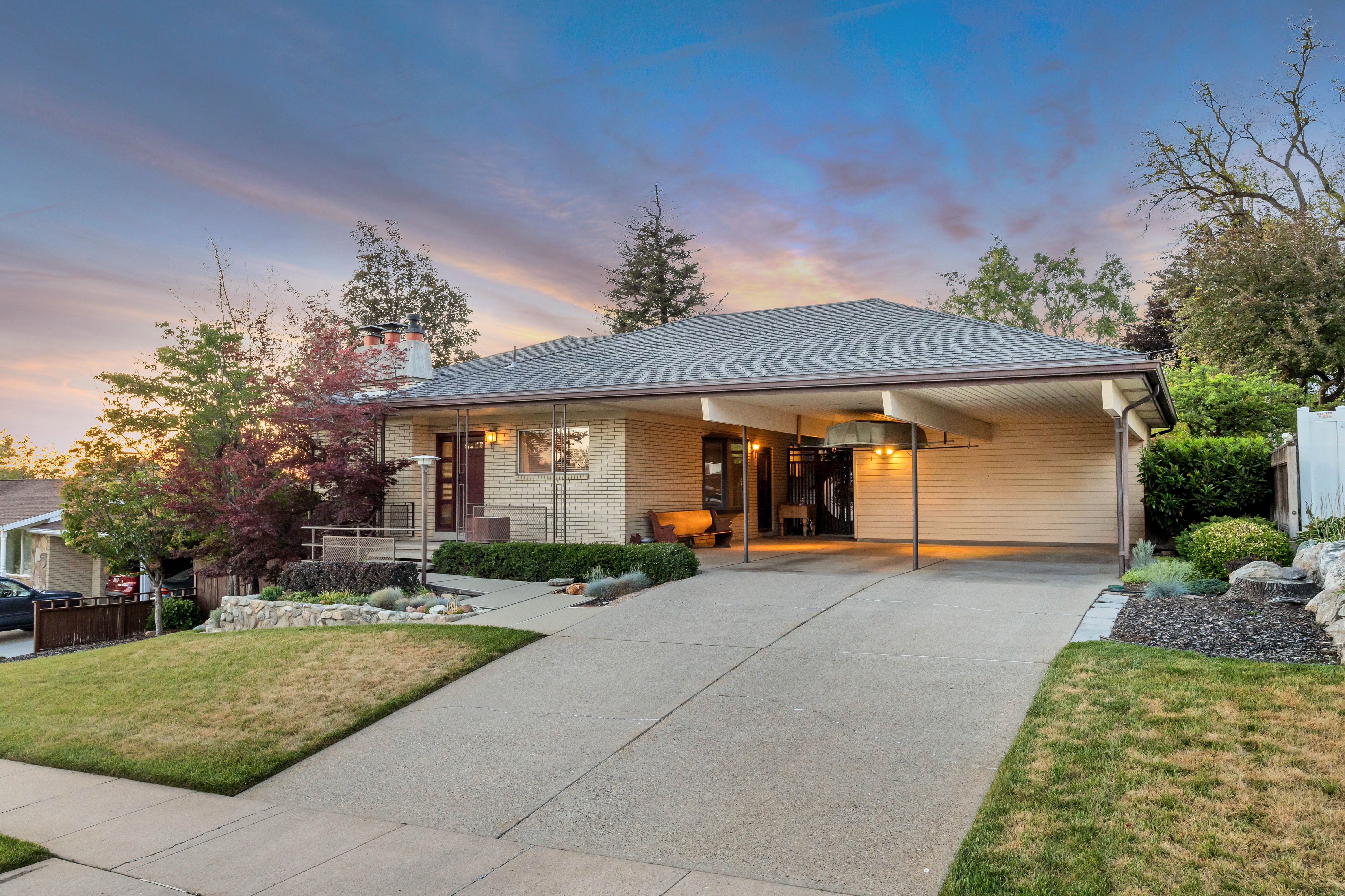 Mid-century residence featuring light-colored brick facade and a covered carport