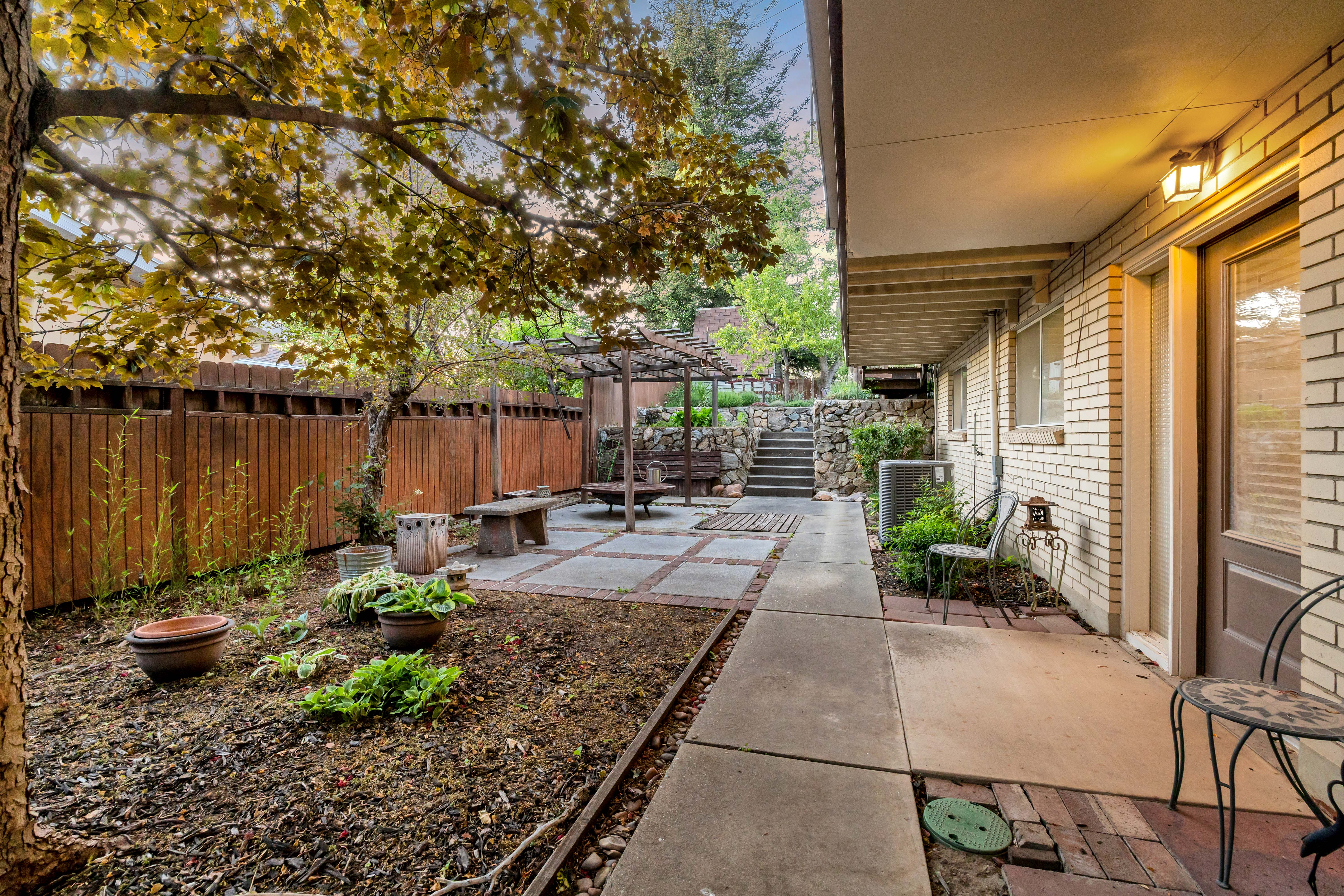 Outdoor patio area featuring a concrete walkway, brick accents, and a landscaped garden bed