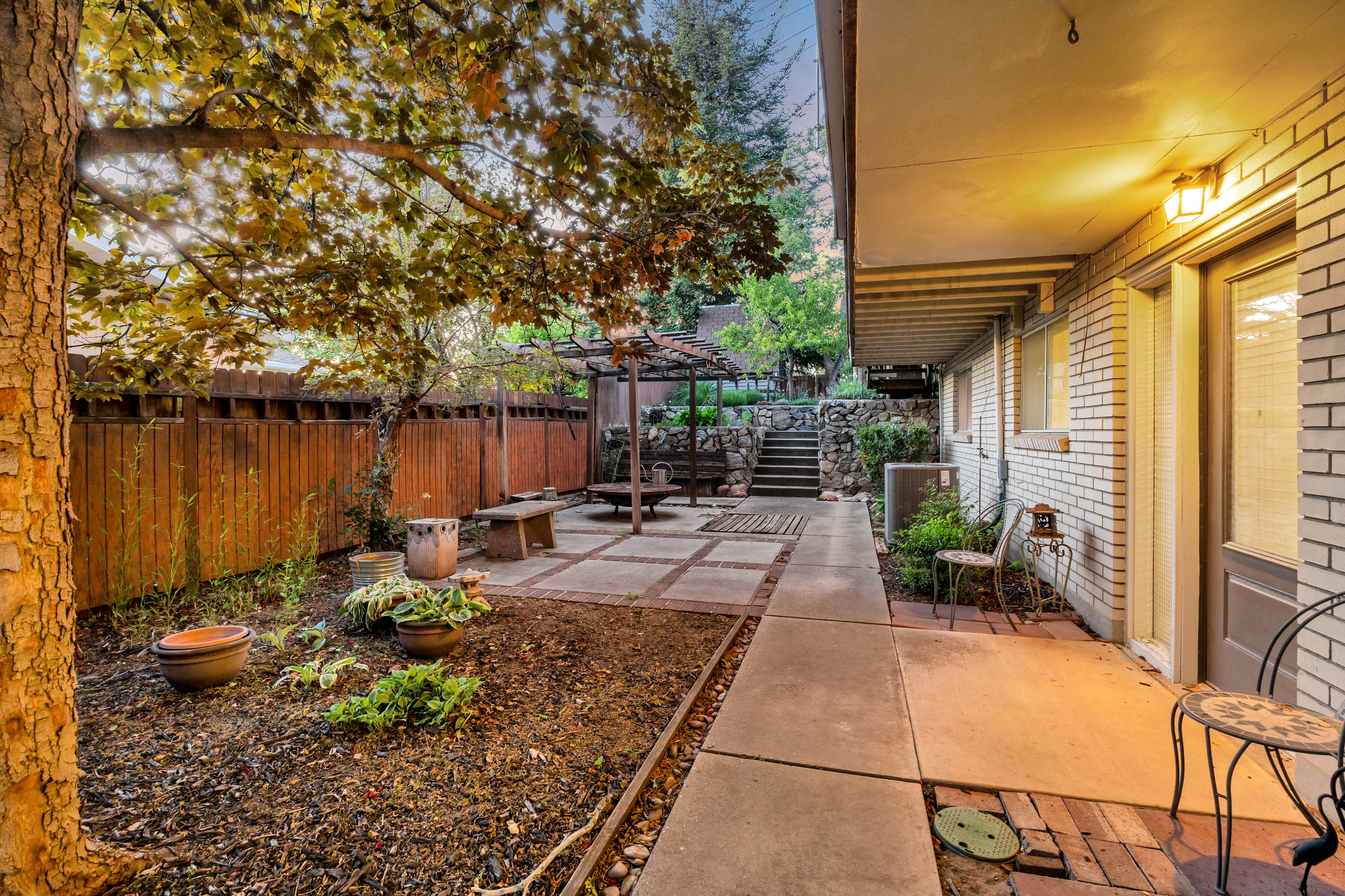 Expansive outdoor patio featuring a pergola, concrete pavers, and a built-in bench