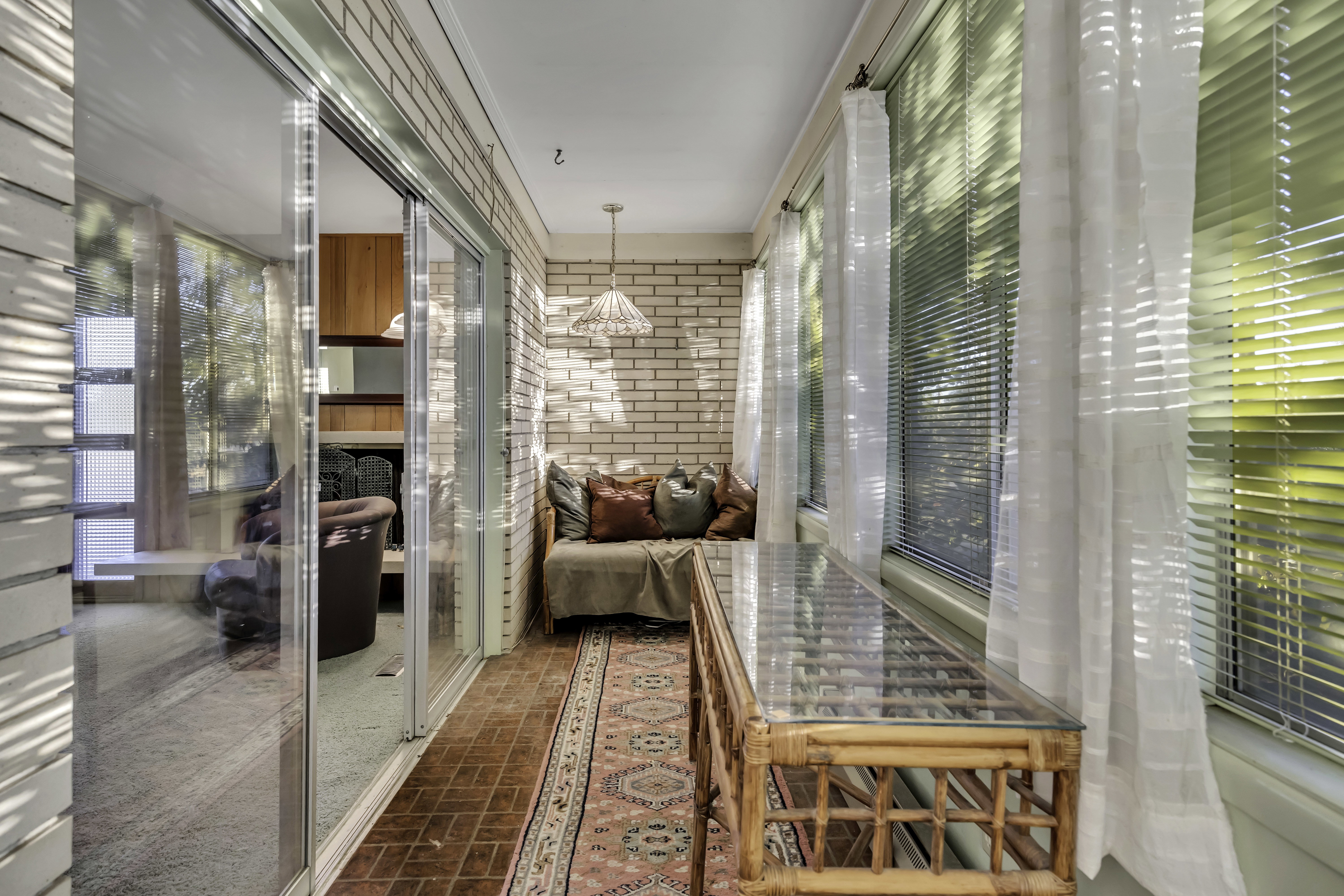 Enclosed sunroom featuring a brick accent wall and tile flooring
