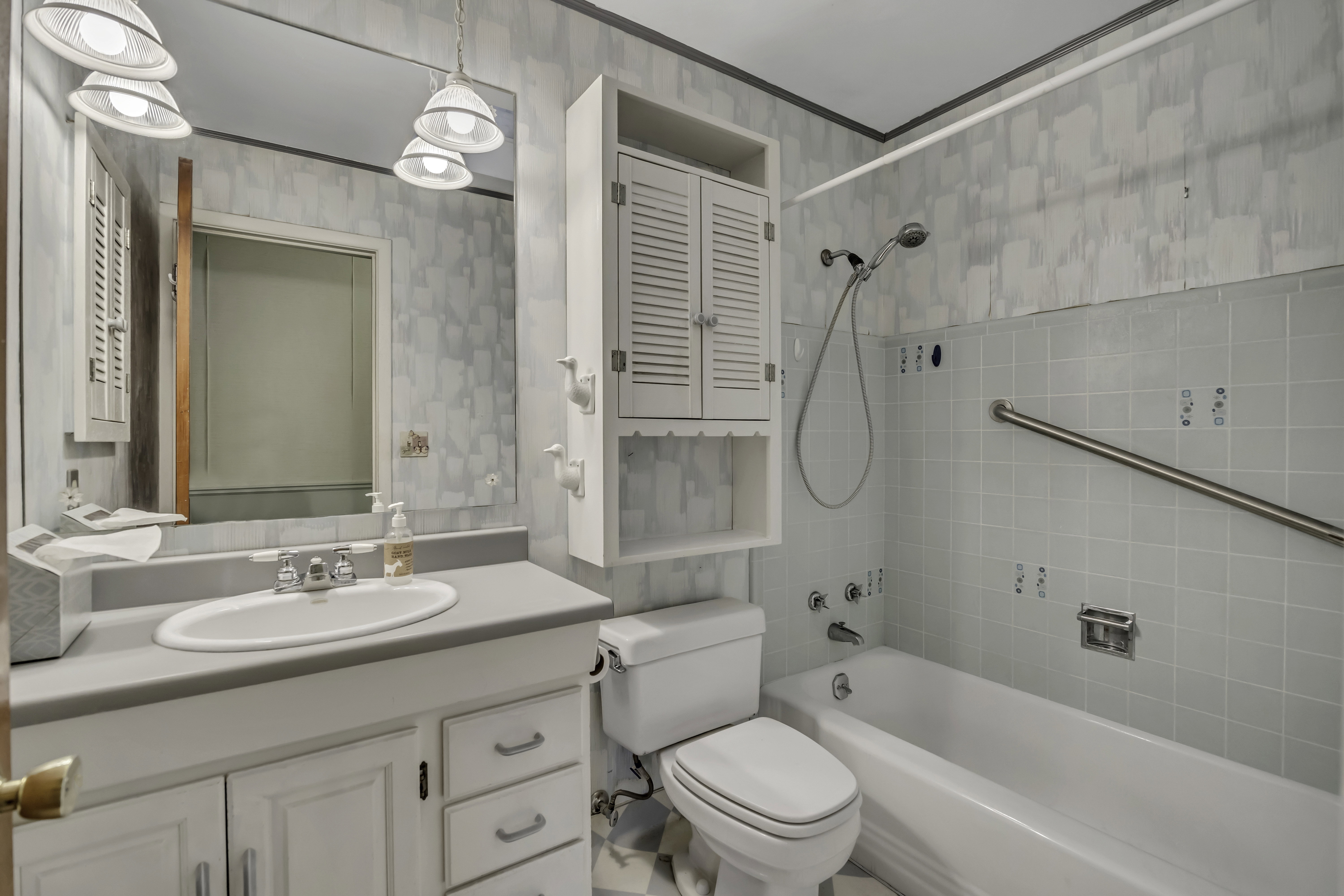 Full bathroom featuring a single vanity with storage cabinetry, a toilet, and a combination tub/shower with tiled surround