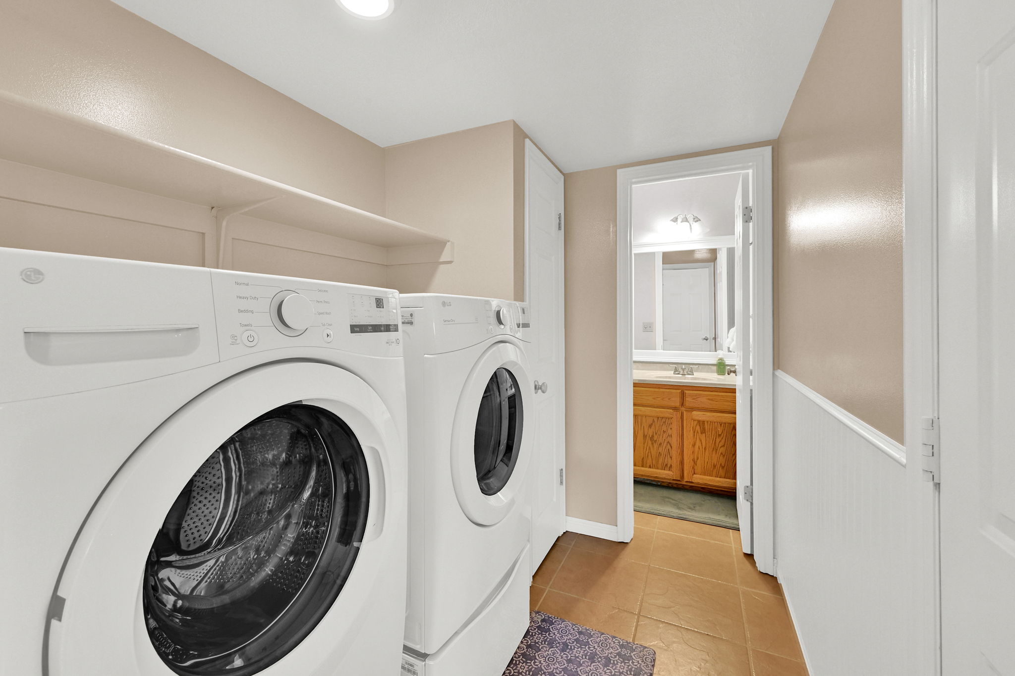 Dedicated laundry area featuring a front-loading washer and dryer, overhead shelving, and recessed lighting