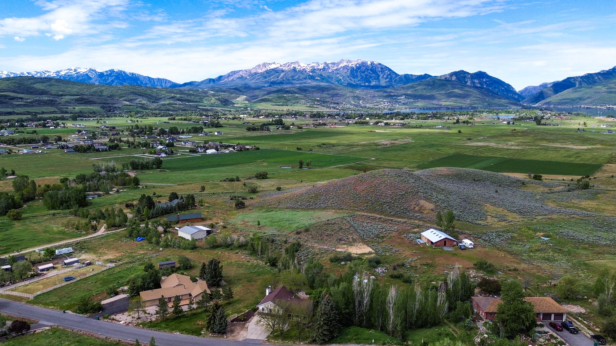 Expansive rural landscape featuring distant snow-capped mountains and scattered residential properties