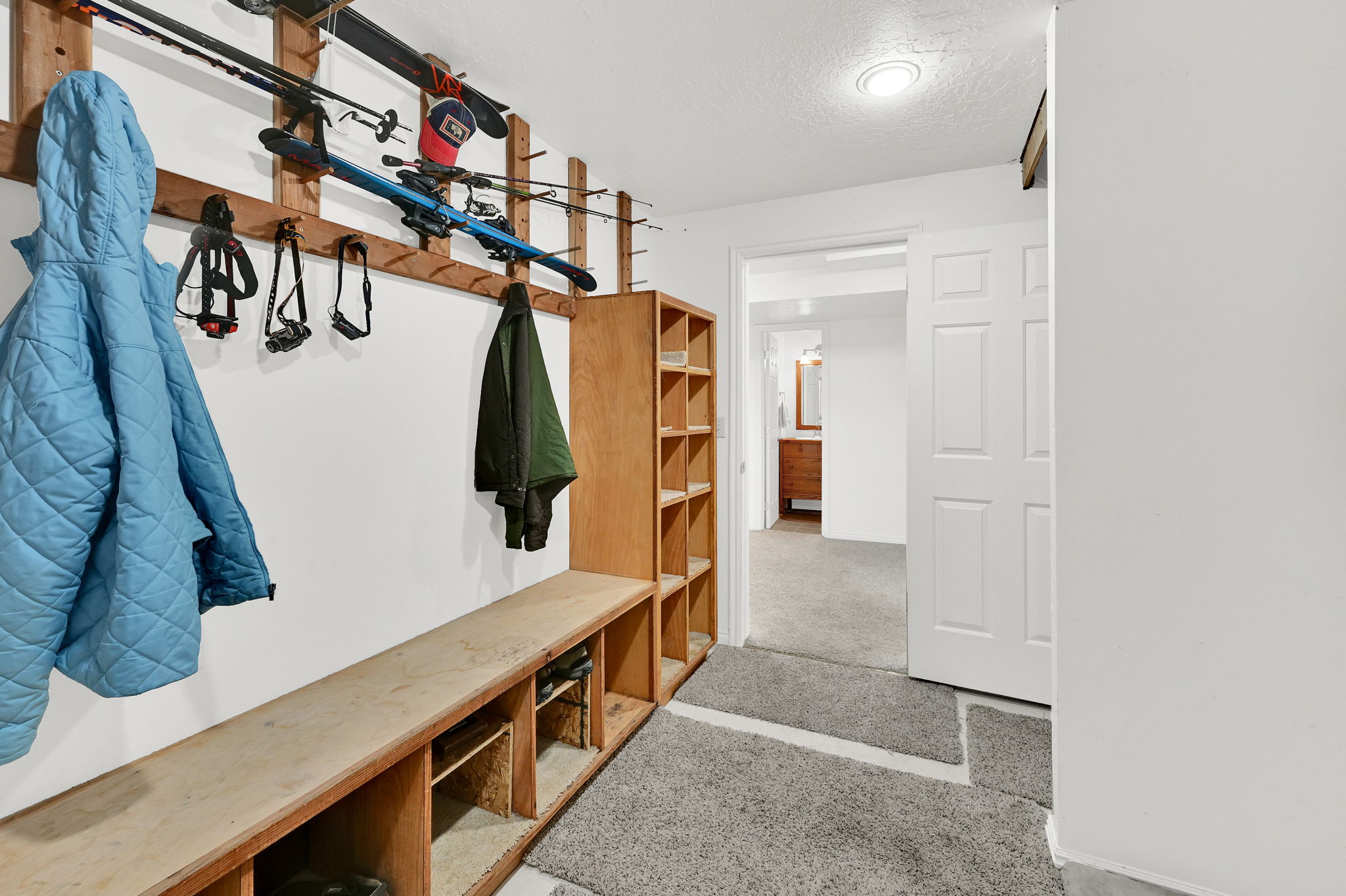 Mudroom featuring built-in wooden shelving, a long wooden bench, and wall-mounted storage racks