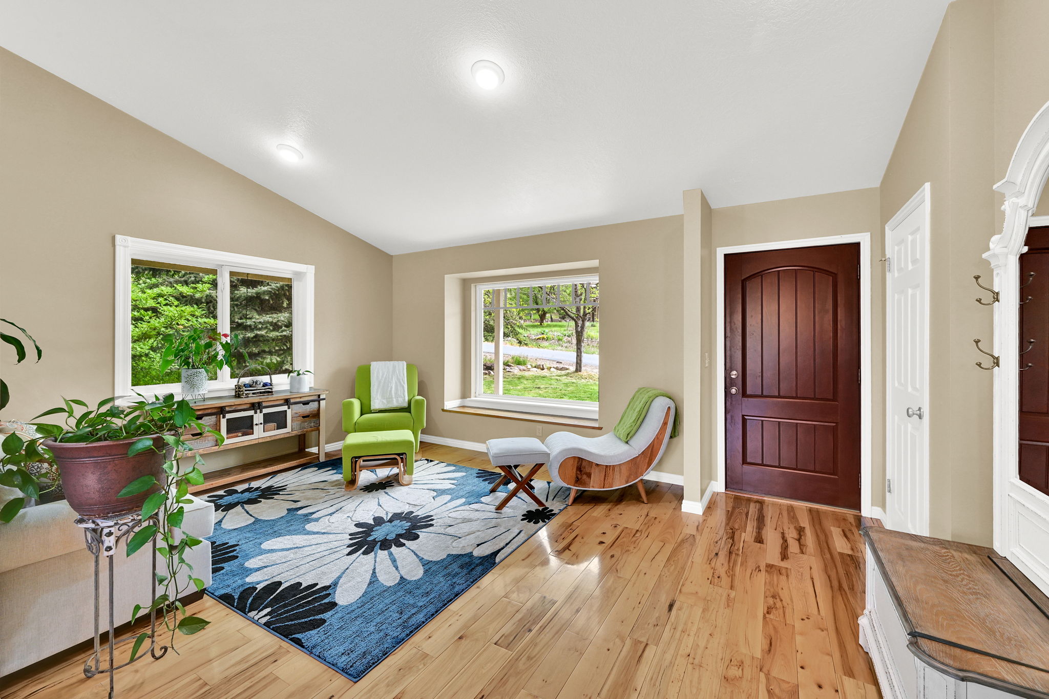 Entryway and living area featuring hardwood flooring, vaulted ceiling, recessed lighting, and large windows with white trim