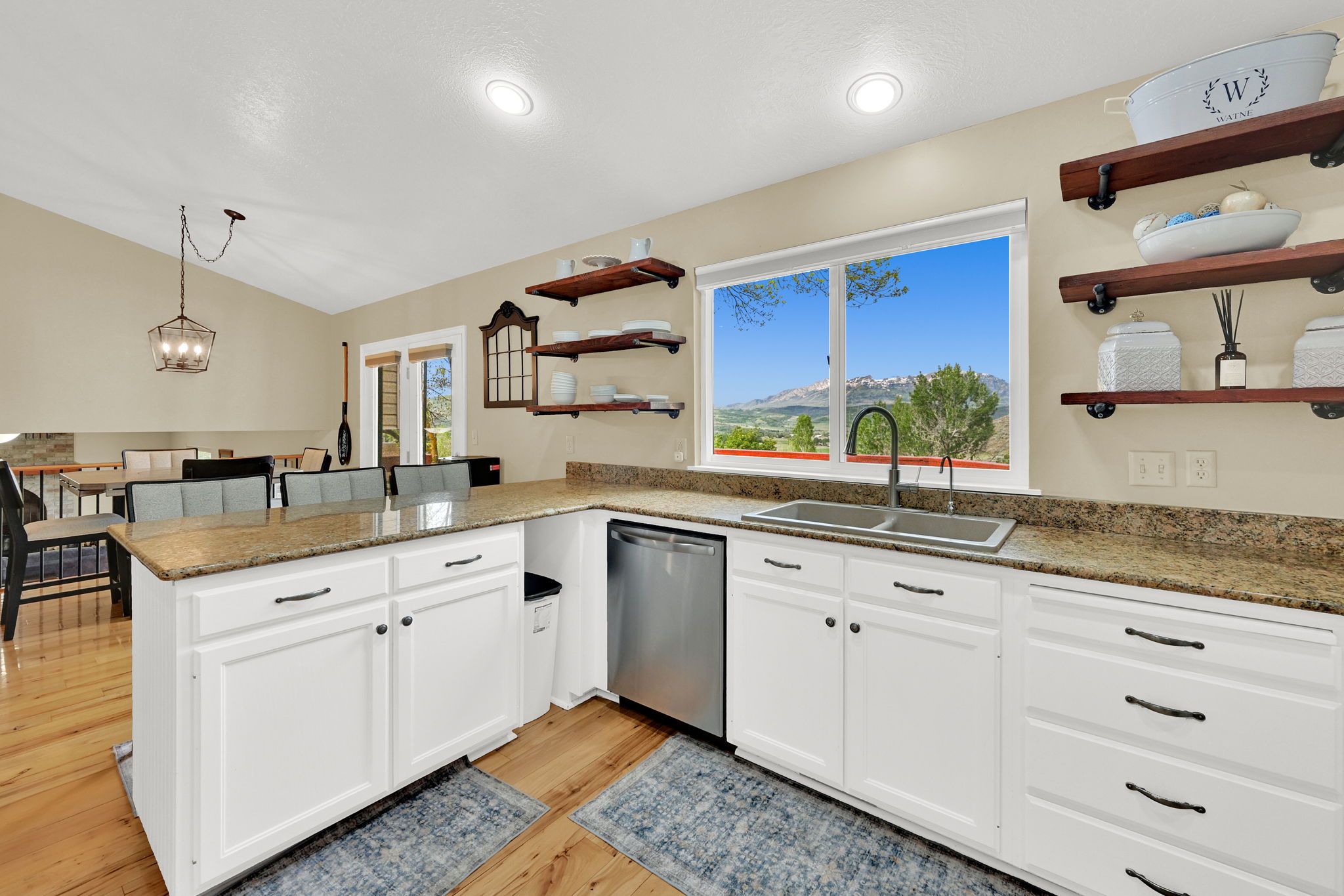 Kitchen featuring white cabinetry with dark hardware, granite-look countertops, and wood-finish flooring