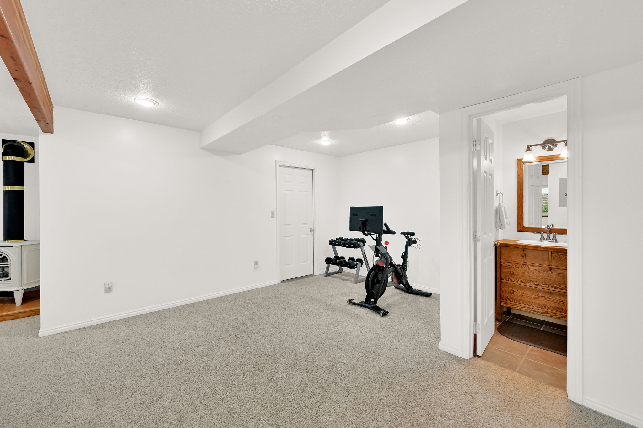 Spacious room with plush carpeting, recessed lighting, and a prominent wood-finish beam