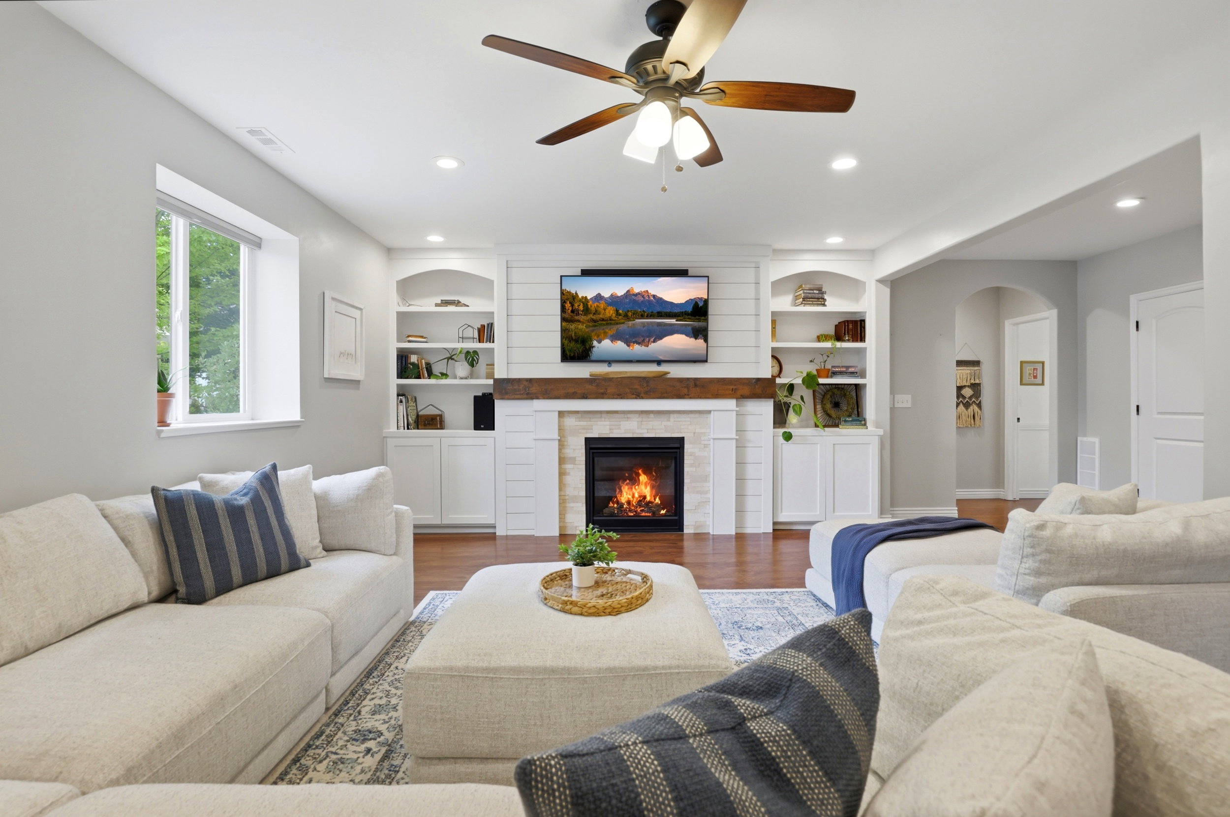Living area featuring a fireplace with a wood mantle and shiplap accents, built-in shelving and cabinetry, recessed lighting, and a ceiling fan