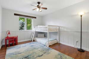 Bright room featuring wood-finish flooring, white paneled wainscoting, and a window with exterior tree greenery