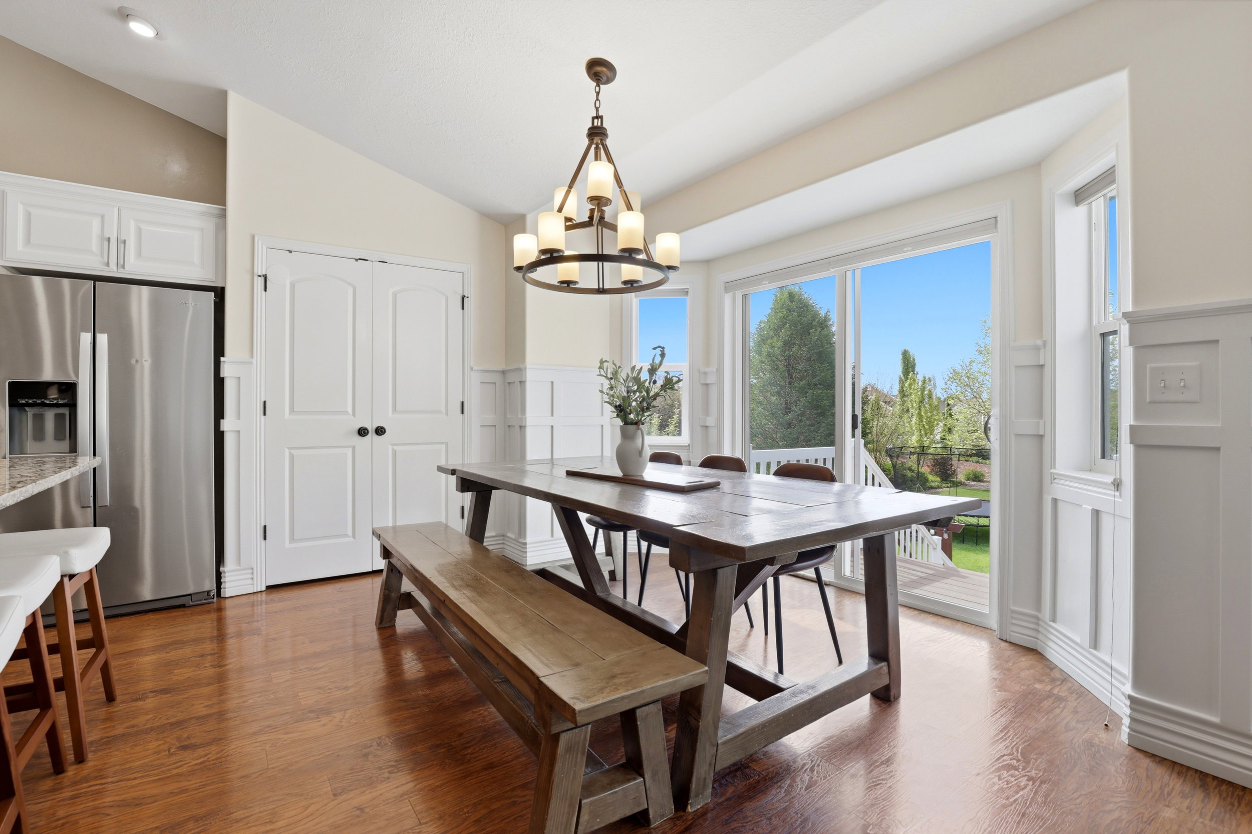 Dining area featuring wood-finish flooring, wainscoting, and a sliding glass door opening to an outdoor deck