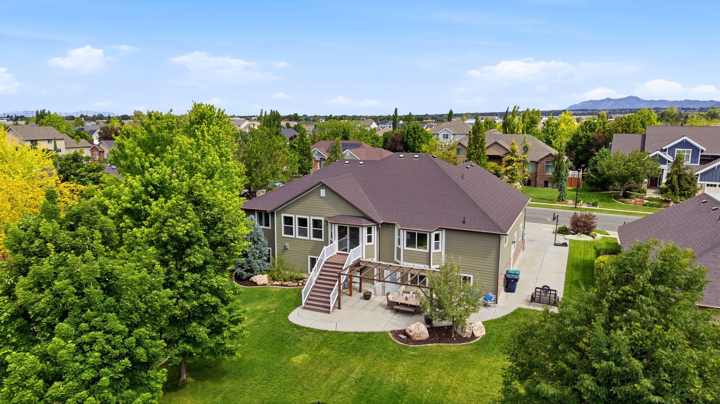 Rear exterior featuring a multi-level deck, a pergola-covered patio, and a spacious lawn