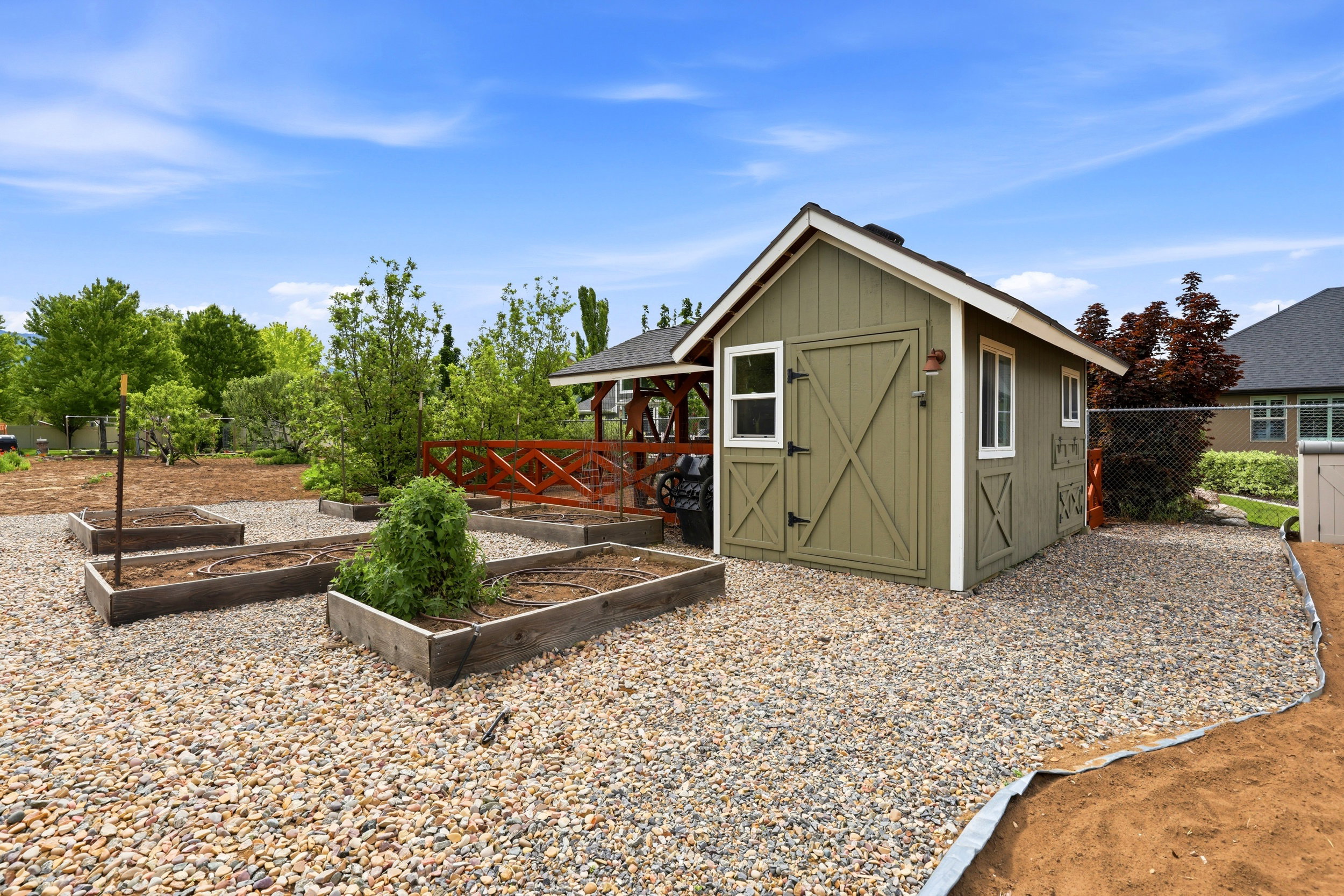 Olive green storage shed with white trim, featuring double barn doors and multiple windows
