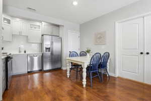 Kitchen featuring wood-finish flooring, white cabinetry, subway tile backsplash, and stainless steel appliances