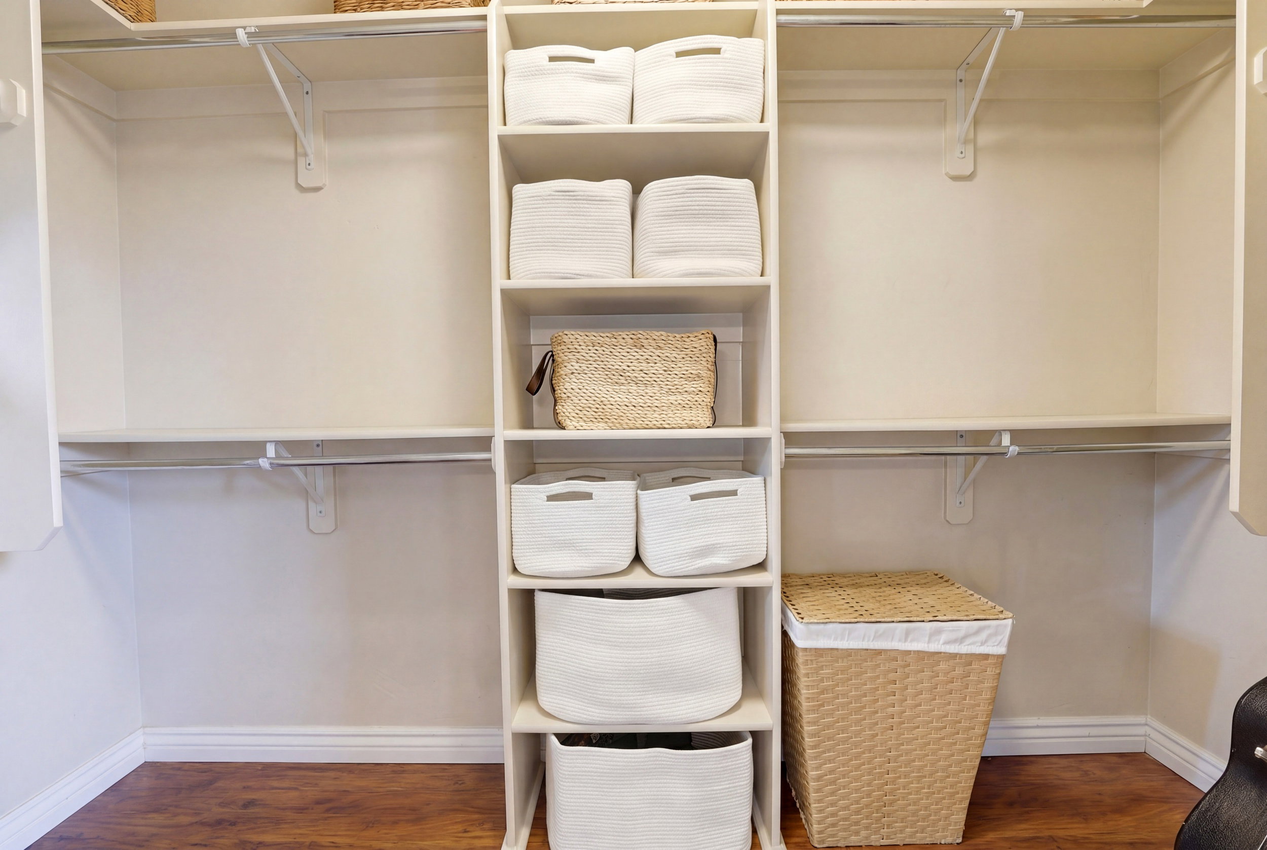 Custom closet system featuring built-in shelving, hanging rods, and wood-finish flooring