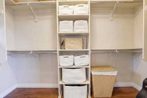 Custom closet system featuring built-in shelving, hanging rods, and wood-finish flooring