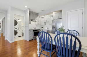 Kitchen with light gray cabinetry, subway tile backsplash, stainless steel appliances, and wood-finish flooring