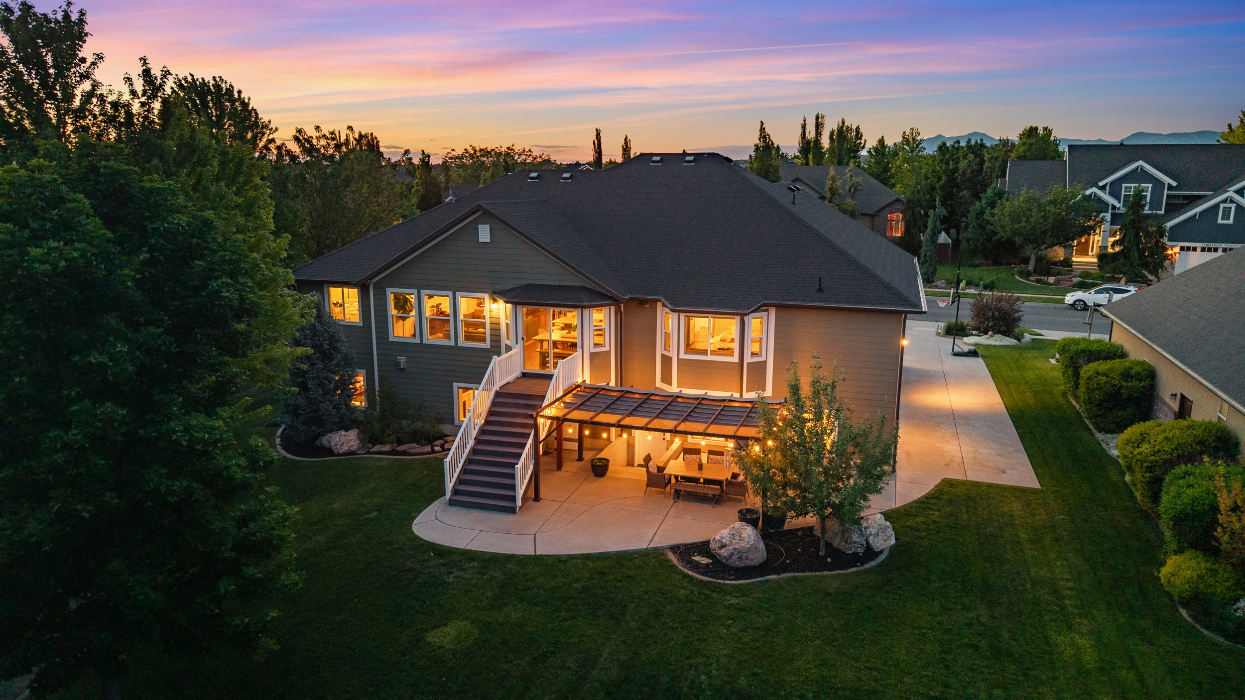 Rear exterior featuring a spacious concrete patio, covered outdoor living area, and a large second-story deck with white railings