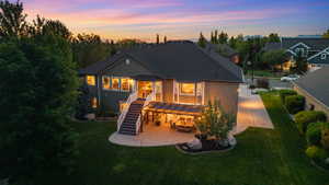 Rear exterior featuring a spacious concrete patio, covered outdoor living area, and a large second-story deck with white railings