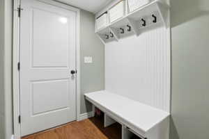 Entryway mudroom featuring a built-in white bench and upper shelving, beadboard paneling, and four black coat hooks