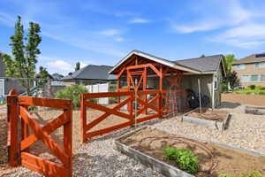 Rear yard featuring a green storage shed with a dark shingle roof, accompanied by an open-air structure with a red wood frame