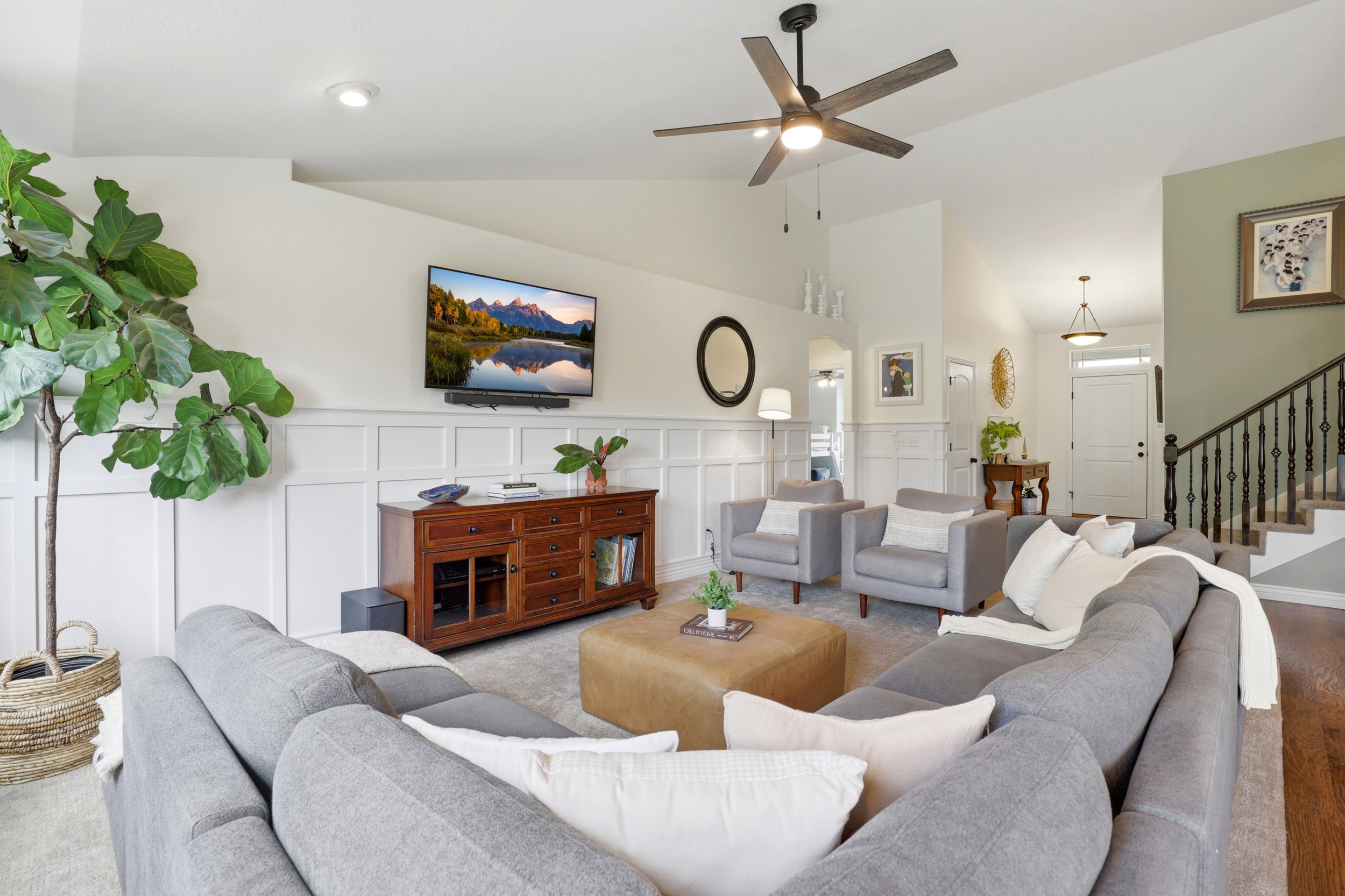 Vaulted ceiling living area featuring wainscoting details, recessed lighting, and a modern ceiling fan