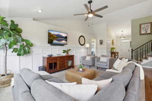 Vaulted ceiling living area featuring wainscoting details, recessed lighting, and a modern ceiling fan
