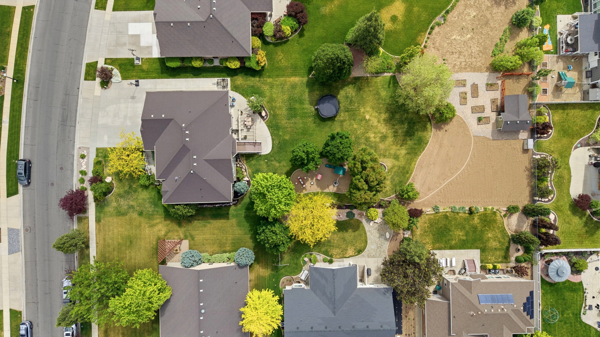 Expansive property featuring a large, manicured lawn, established trees, and a spacious rear patio