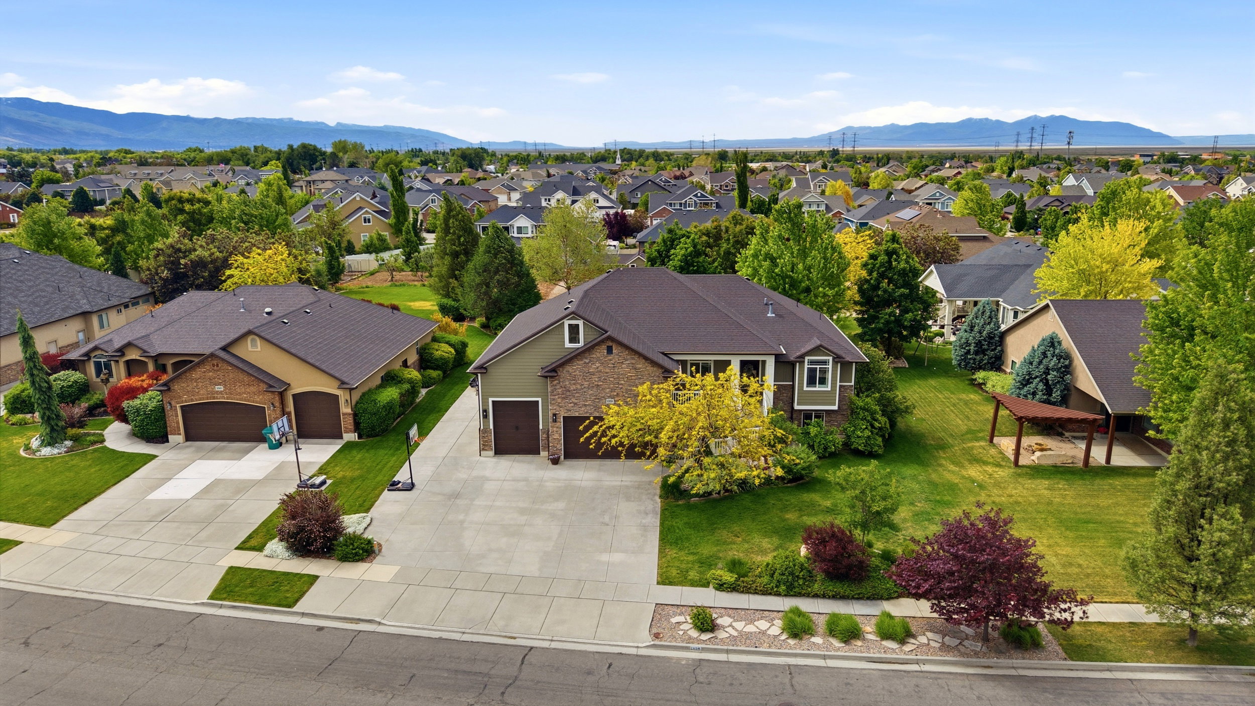 Expansive residential lot featuring a two-story home with a two-car garage, mature landscaping, and an extended concrete driveway