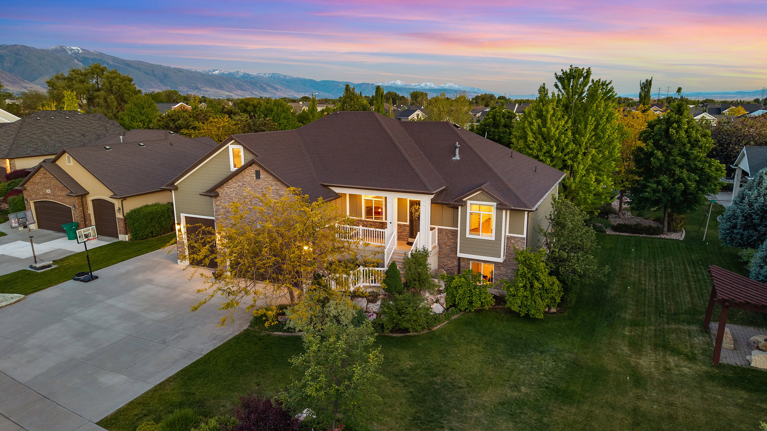Spacious residential property featuring a stone and siding exterior, a two-car garage, and a wide driveway