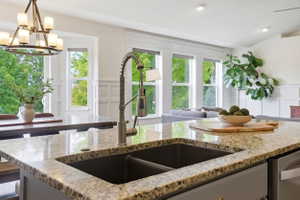 Kitchen island featuring a granite countertop, dual basin sink with pull-down faucet, and integrated dishwasher