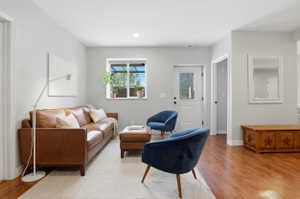 Living area featuring wood-finish flooring, light gray walls, a window with exterior views, and a white door with a window pane