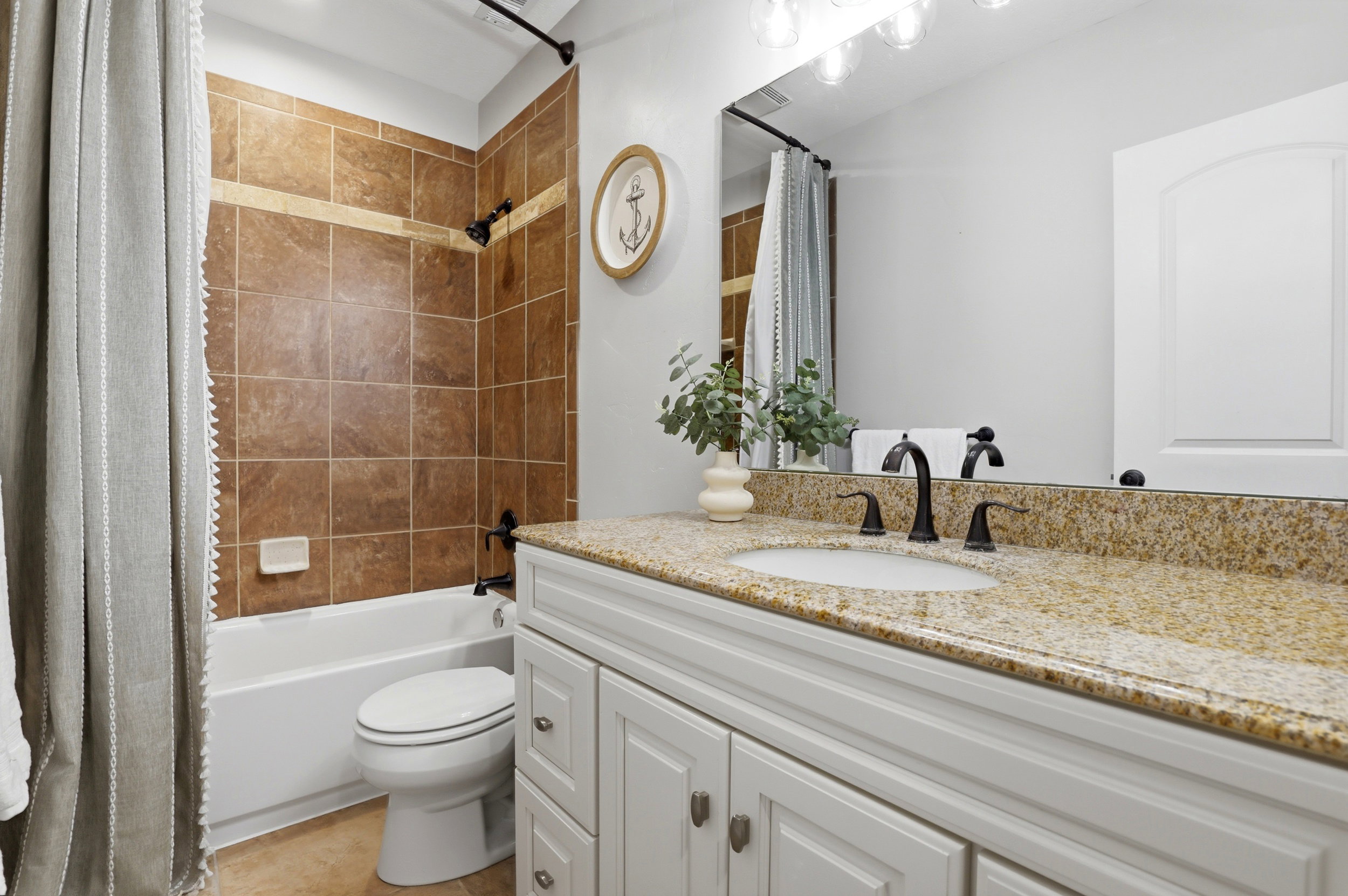 Bathroom featuring a white vanity with recessed panel cabinetry and a speckled stone countertop