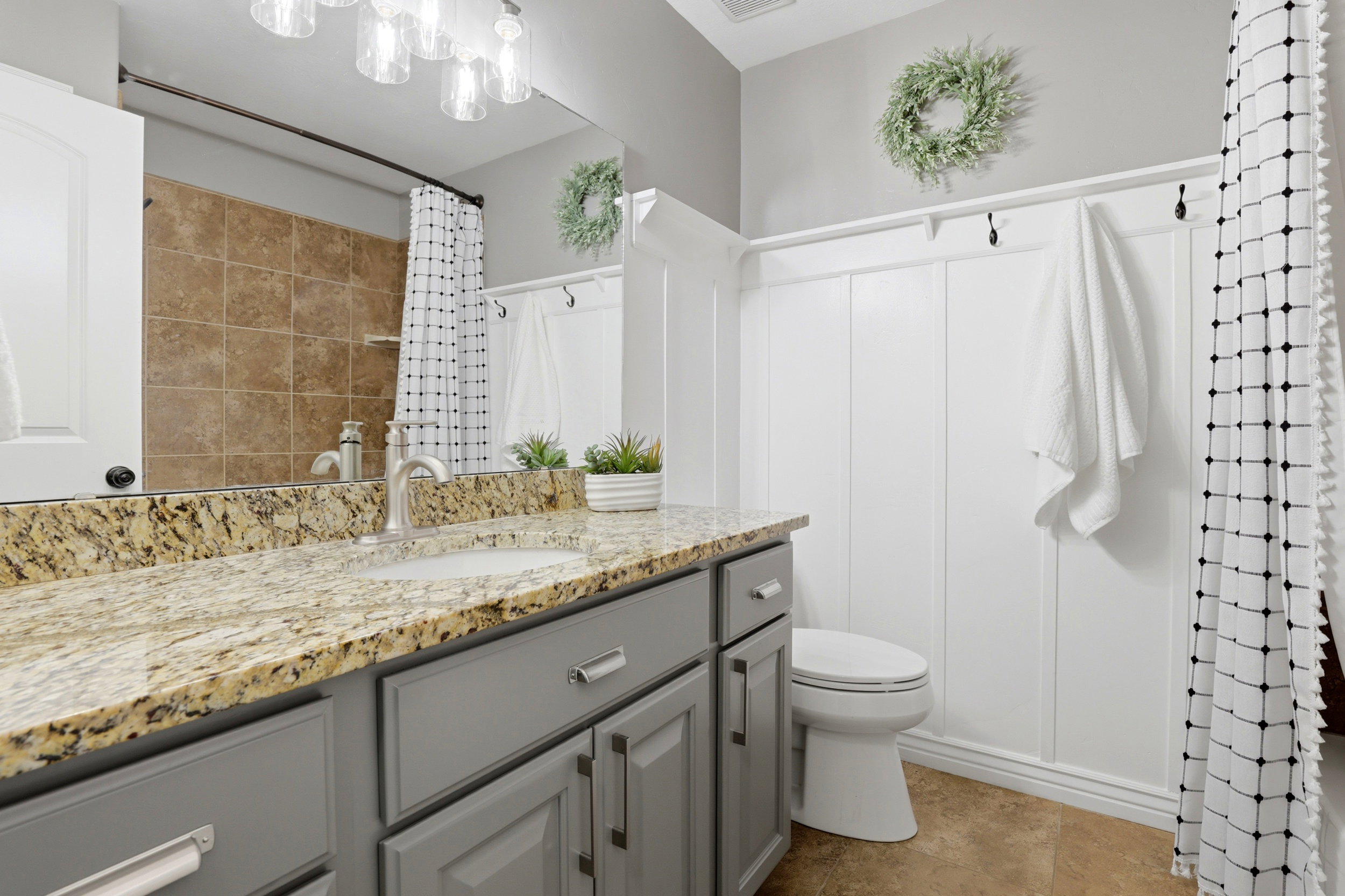 Bathroom featuring a single vanity with stone countertop, undermount sink, and brushed nickel faucet