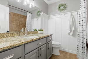 Bathroom featuring a single vanity with stone countertop, undermount sink, and brushed nickel faucet