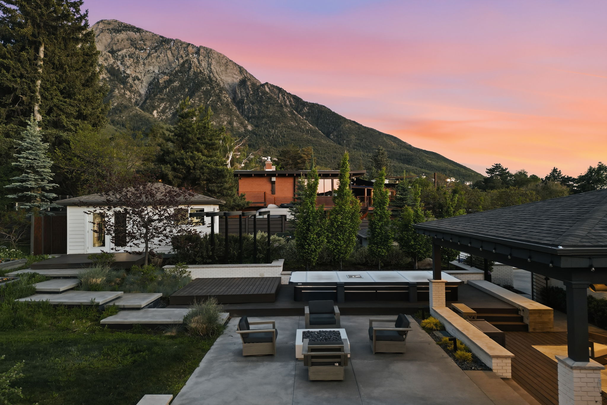 Outdoor living area featuring a concrete patio, built-in fire pit, and covered patio space with a shingled roof