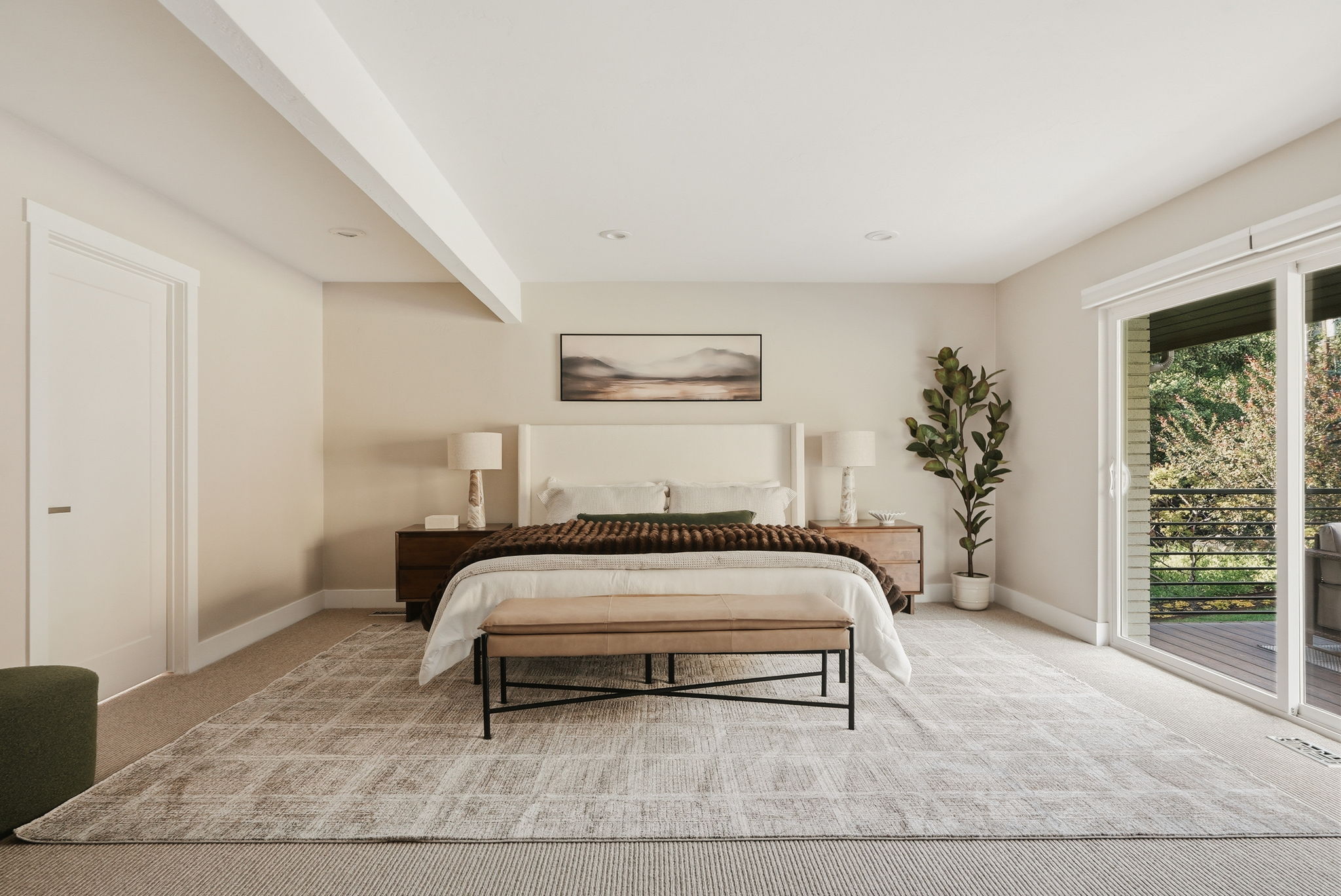 Spacious room with plush carpet flooring, recessed lighting, and a prominent sliding glass door leading to an outdoor deck
