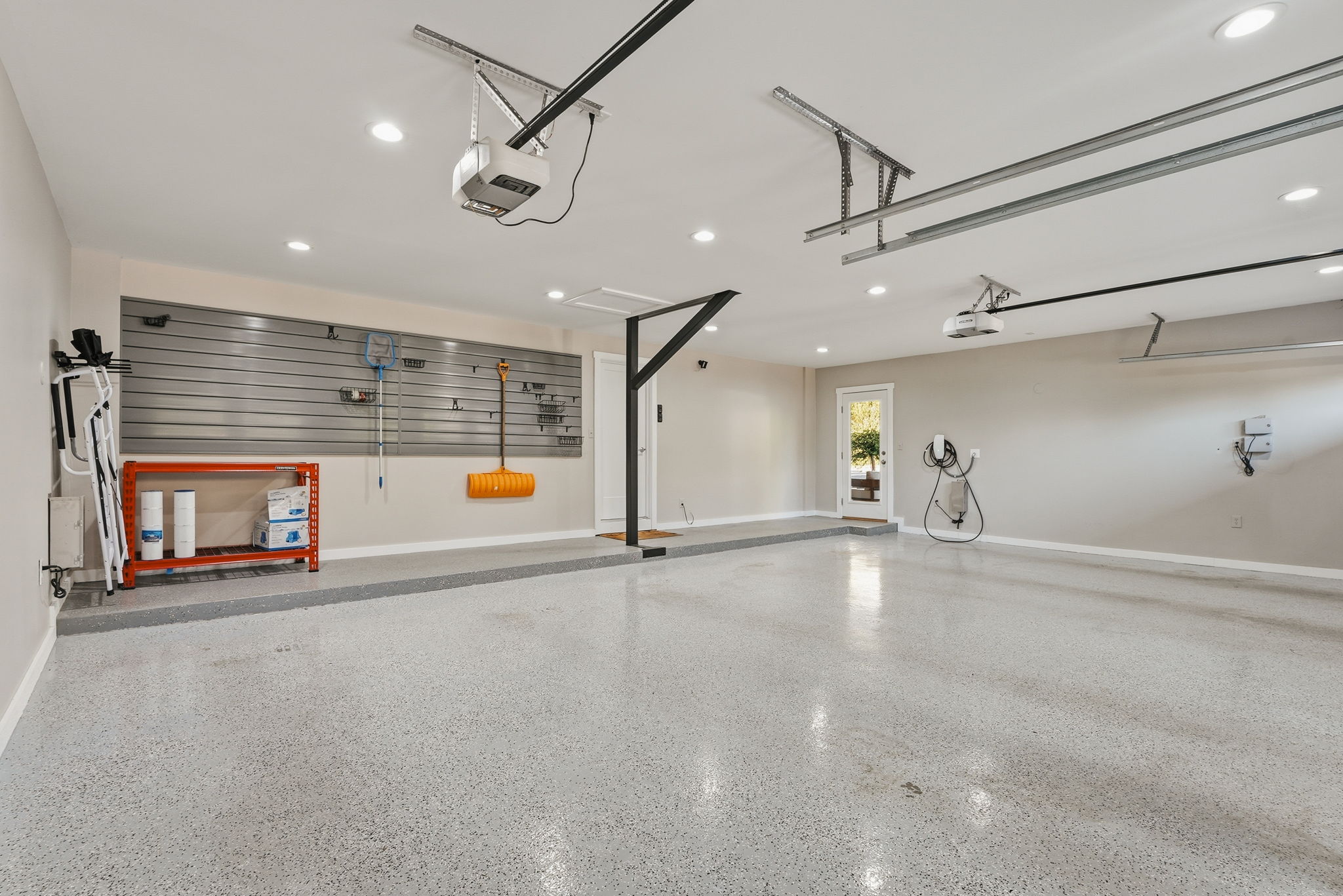 Spacious garage featuring a durable epoxy floor finish, recessed lighting, and an EV charging station