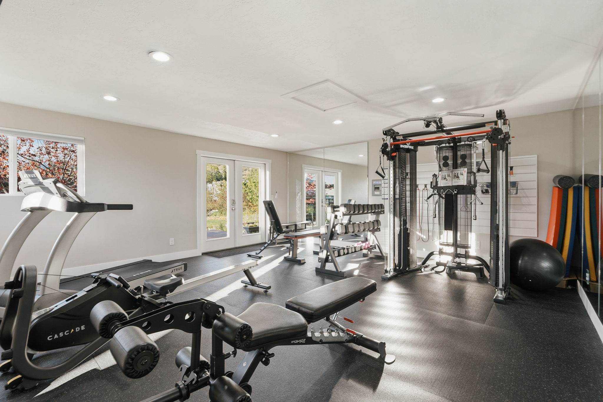 Dedicated fitness space featuring rubber flooring, recessed lighting, and a large mirror wall