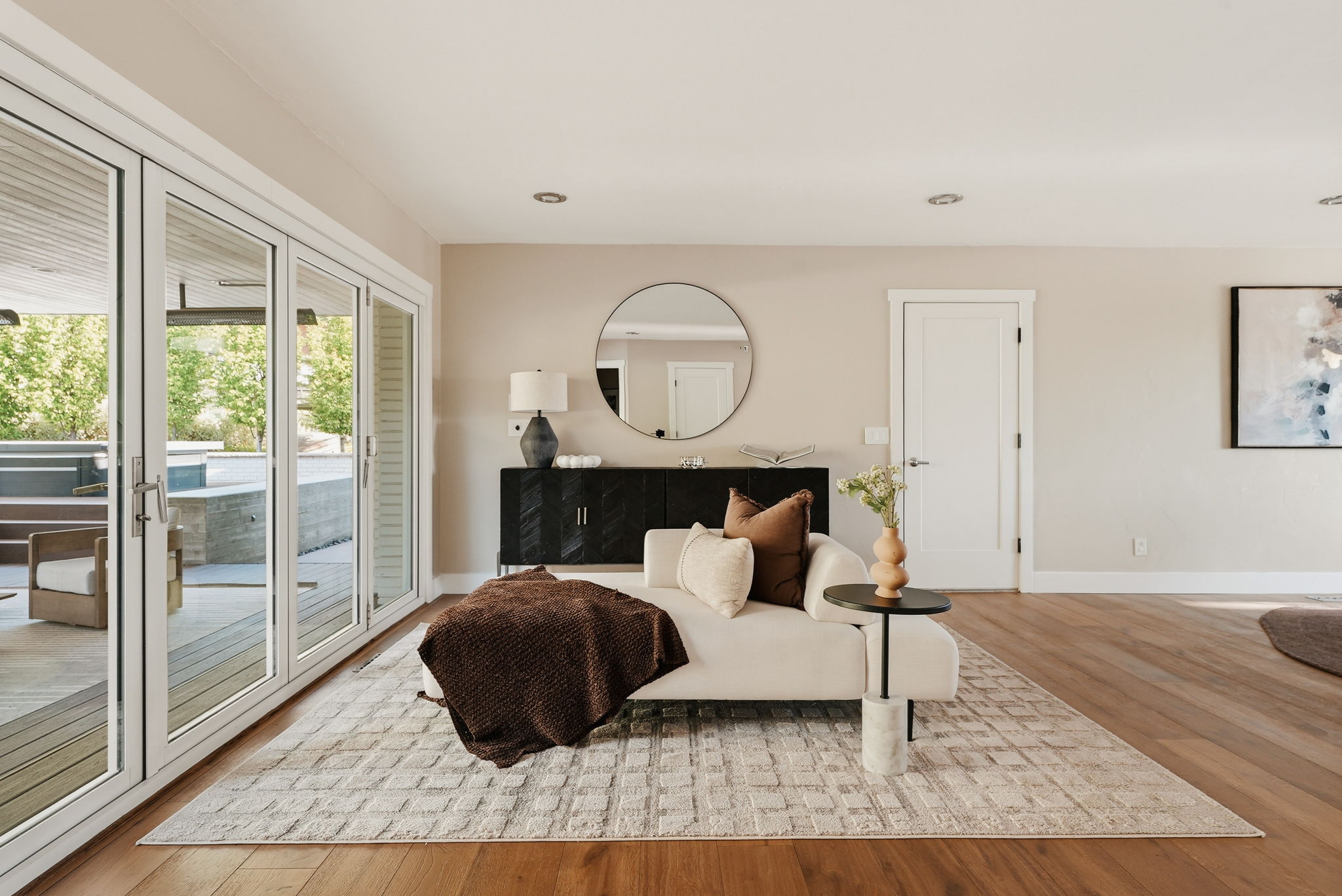 Expansive multi-panel glass doors open to an outdoor patio with a built-in stone feature