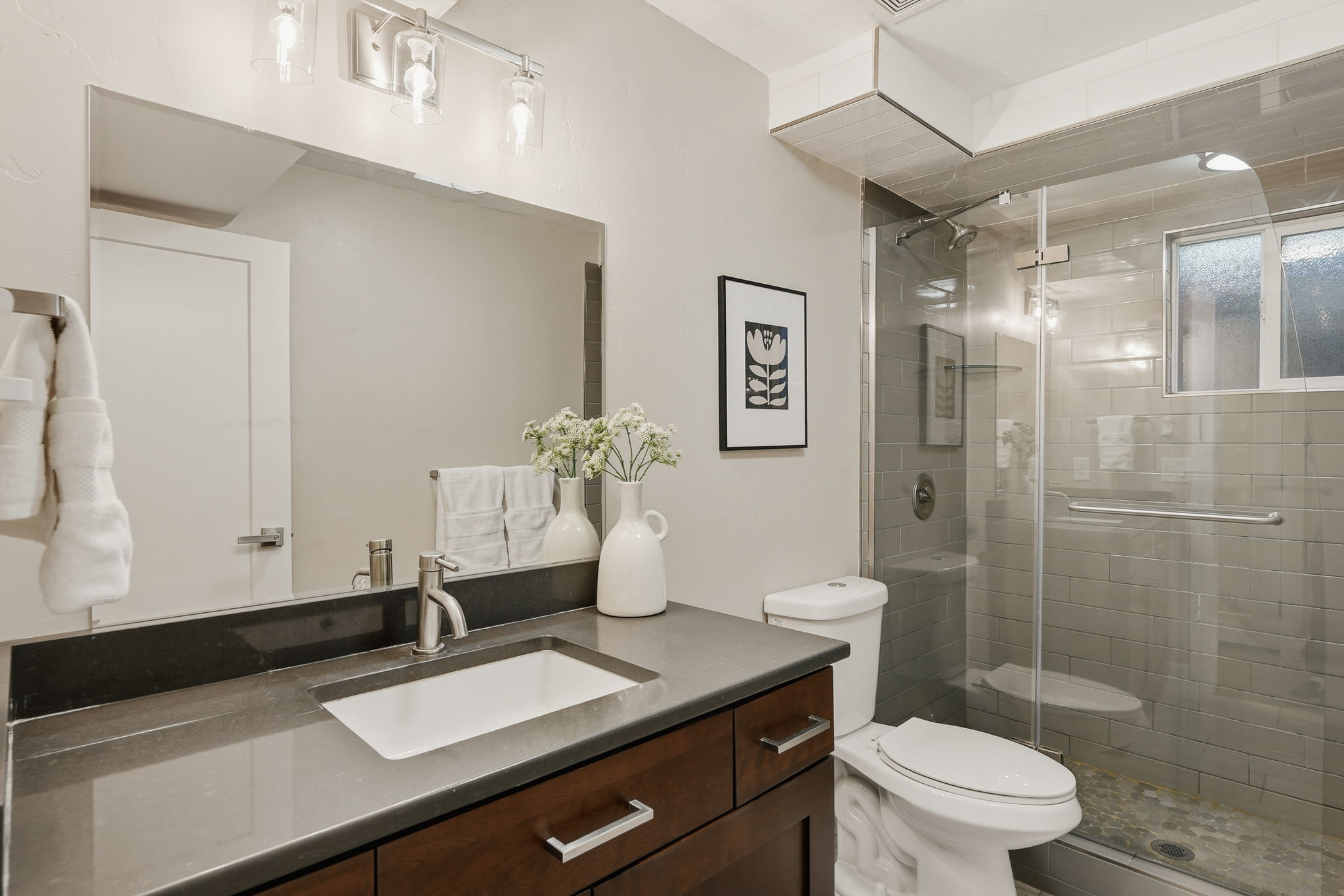 Bathroom featuring a dark wood-finish vanity with a rectangular undermount sink, a gray countertop, and a brushed nickel faucet