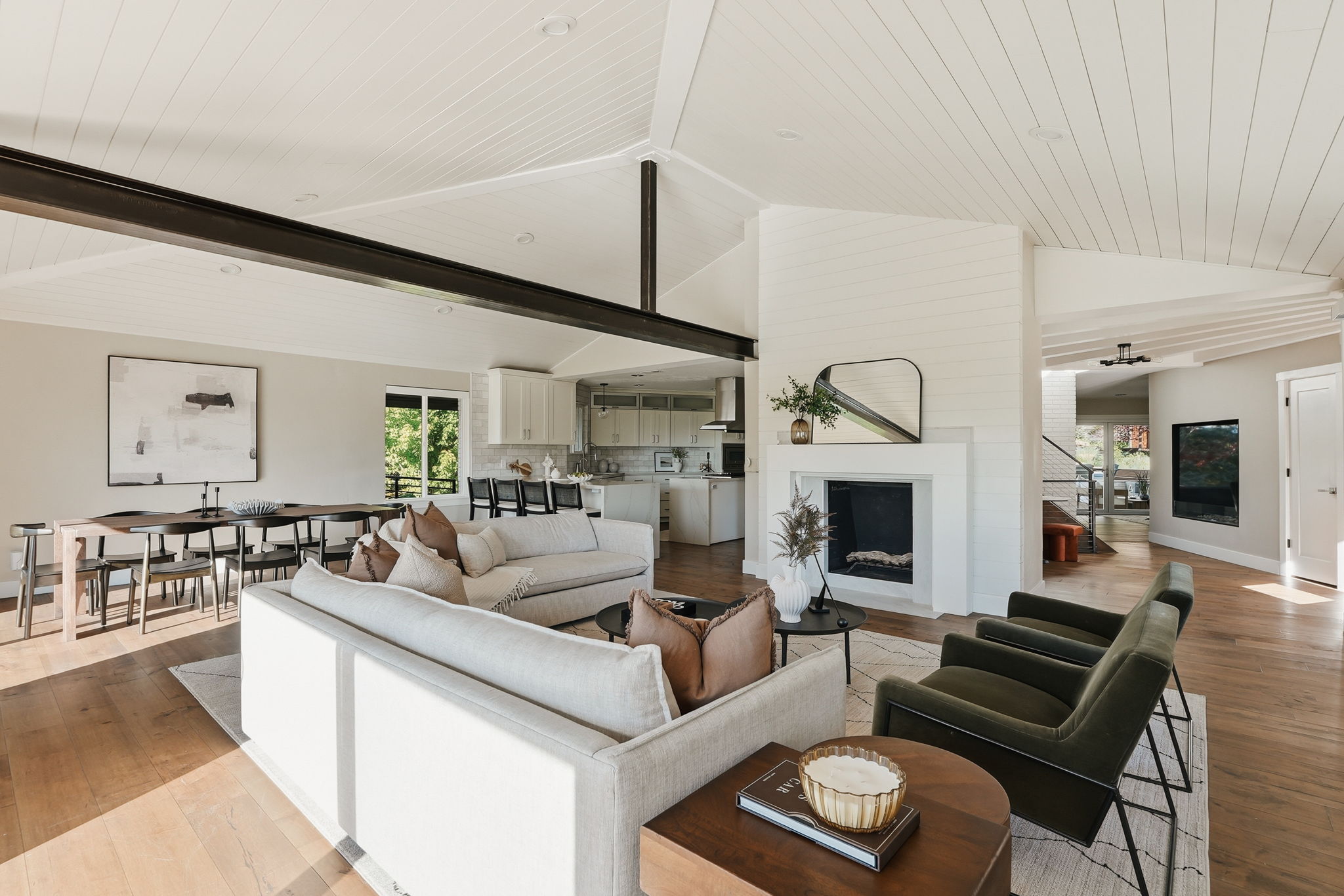 Open-concept living area with vaulted plank ceilings, exposed structural beams, a fireplace, wood-finish flooring, and a dining area