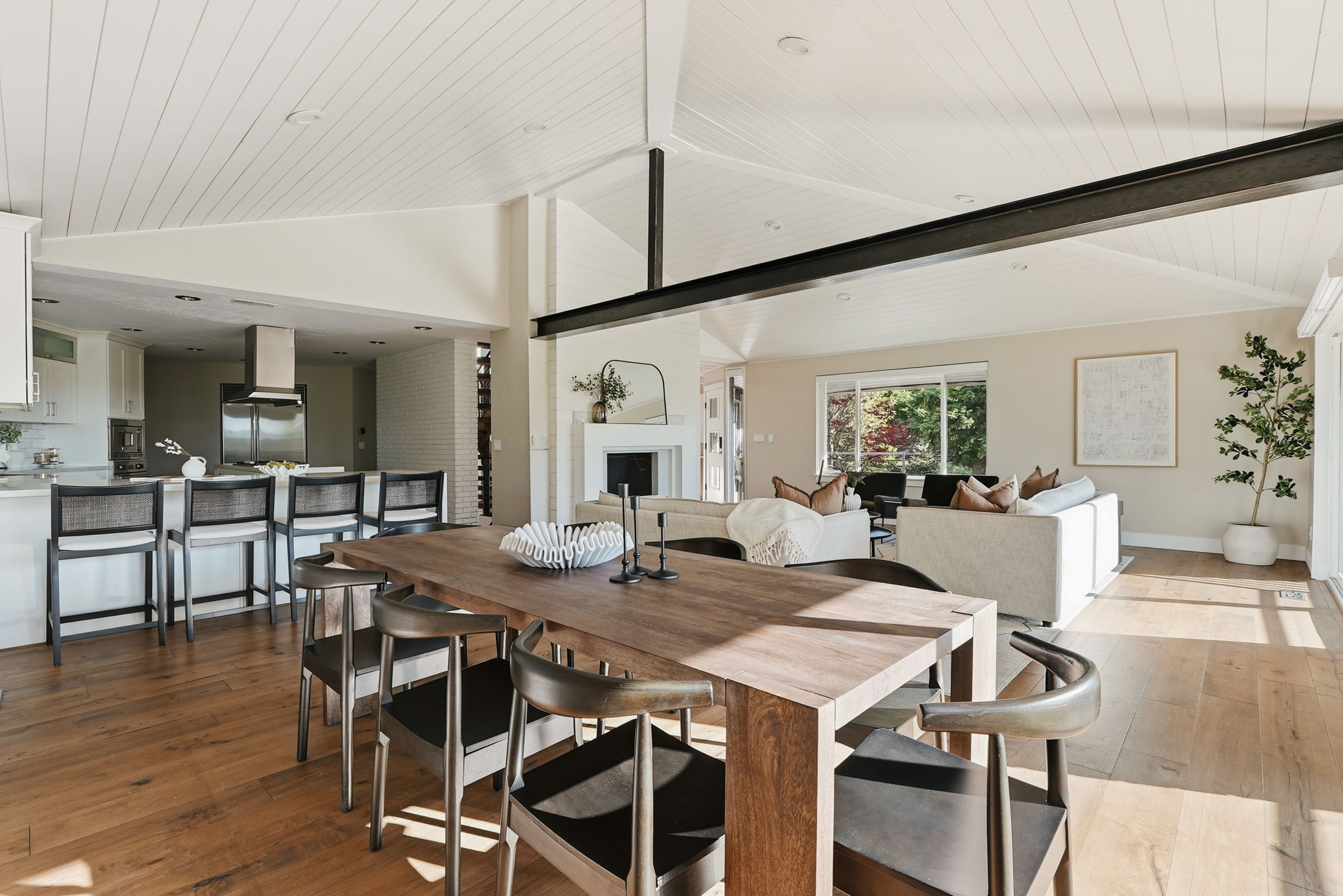 Expansive open-concept living area featuring a vaulted ceiling with white wood paneling and exposed structural beam
