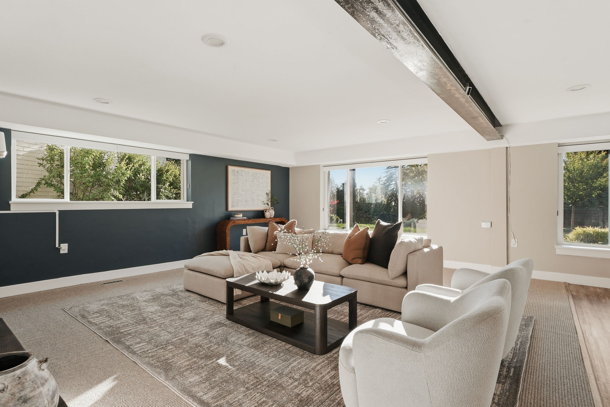 Spacious living area featuring a prominent exposed beam, recessed lighting, and multiple windows