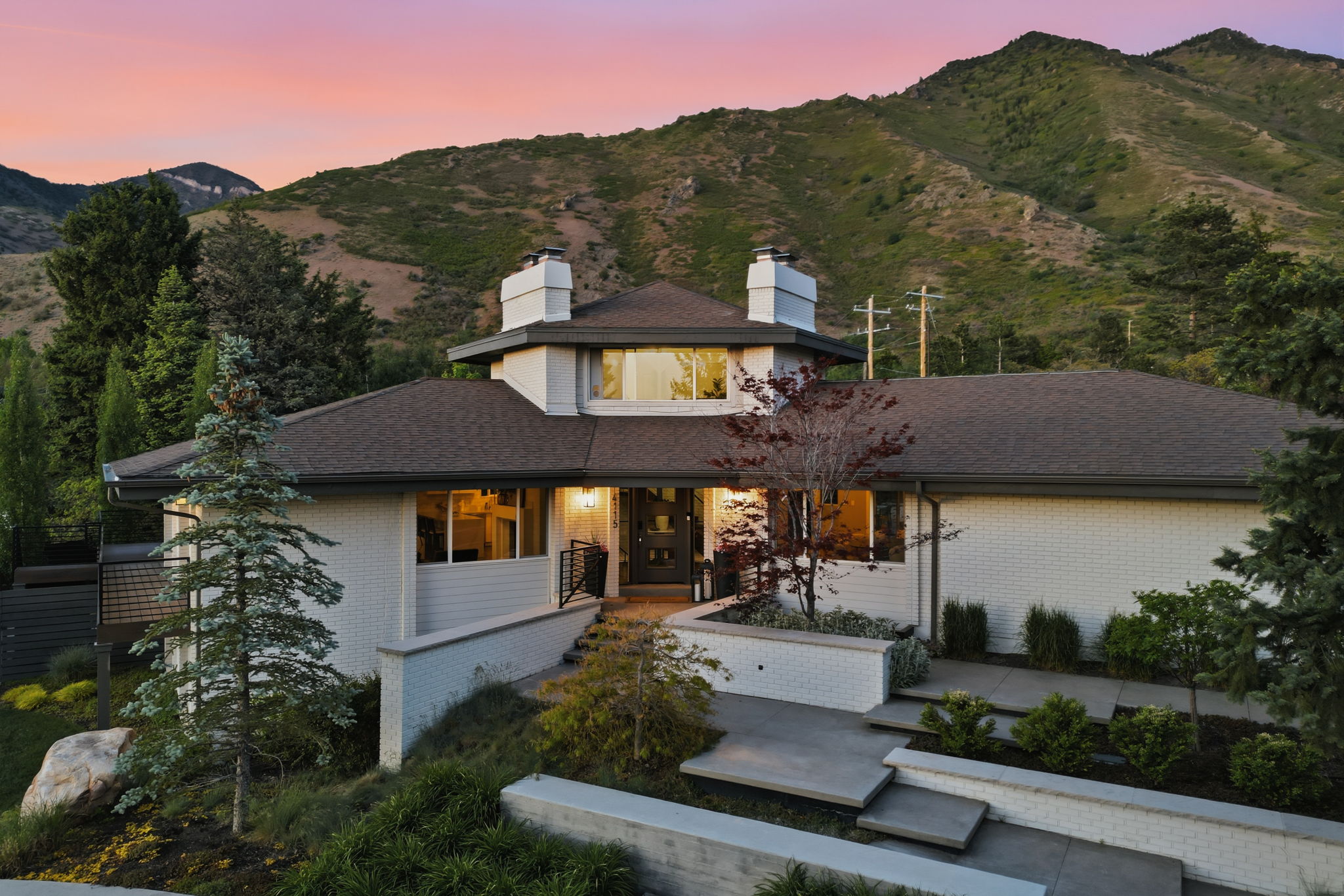 Multi-level residence featuring white brick and siding exterior, dark shingle roofing, and multiple chimneys