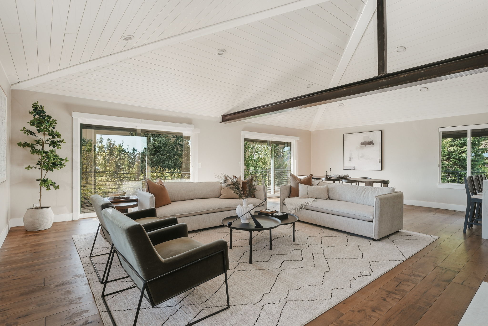 Spacious living area featuring a vaulted ceiling with exposed beams, recessed lighting, and wood-finish flooring