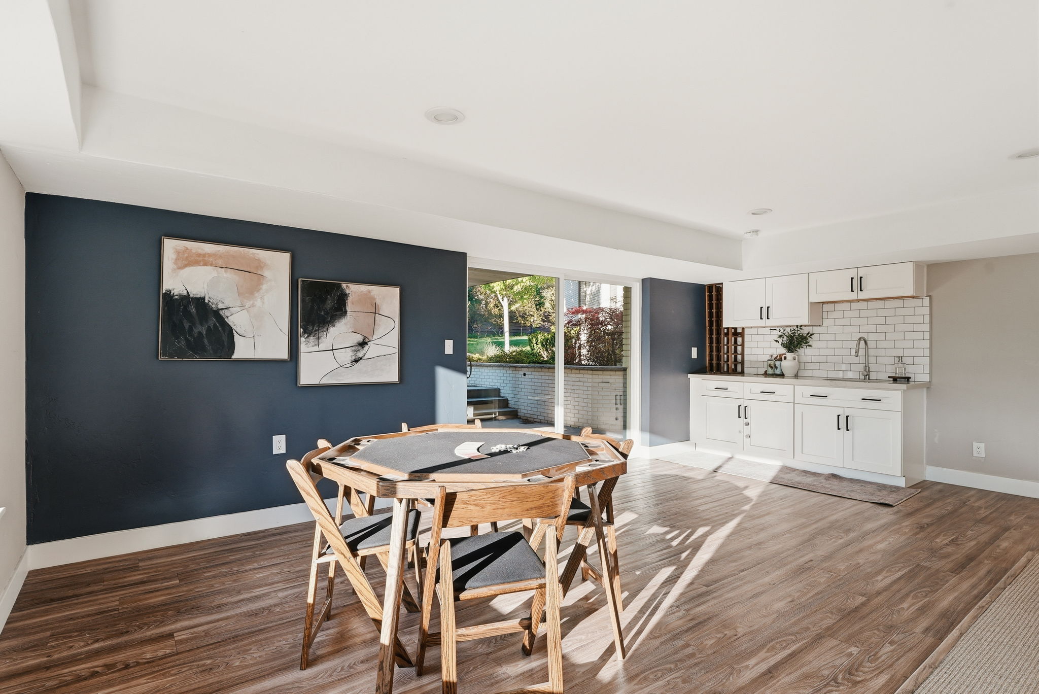 Spacious open-concept room featuring wood-finish flooring, recessed lighting, and a prominent accent wall