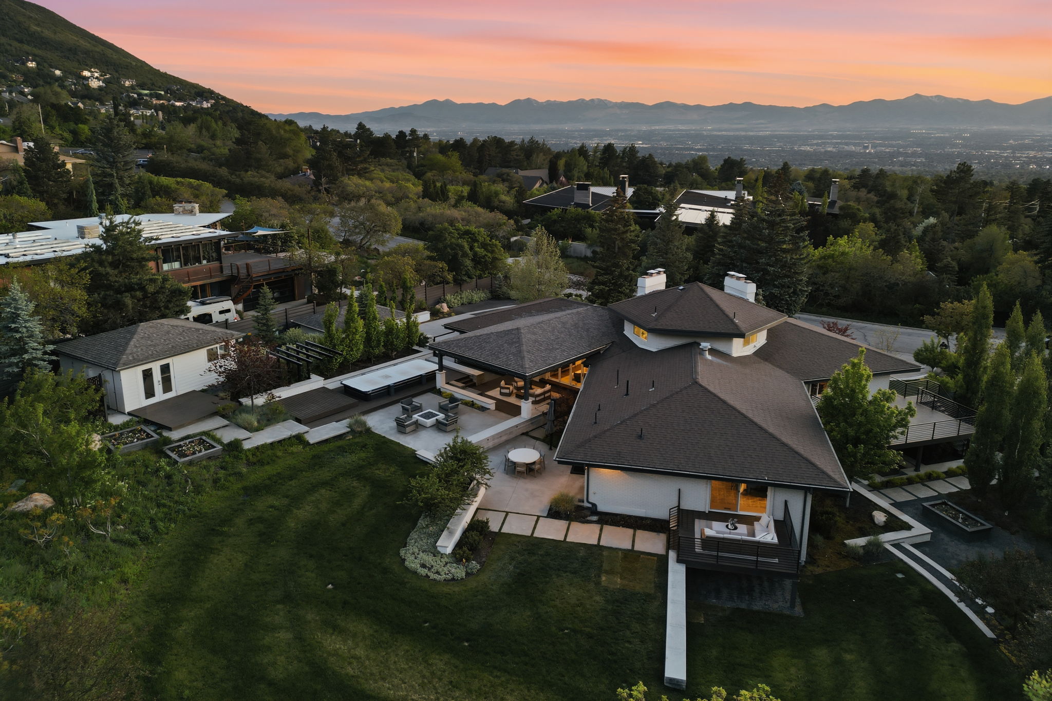Expansive property featuring a multi-level residence with a dark shingle roof and multiple chimneys