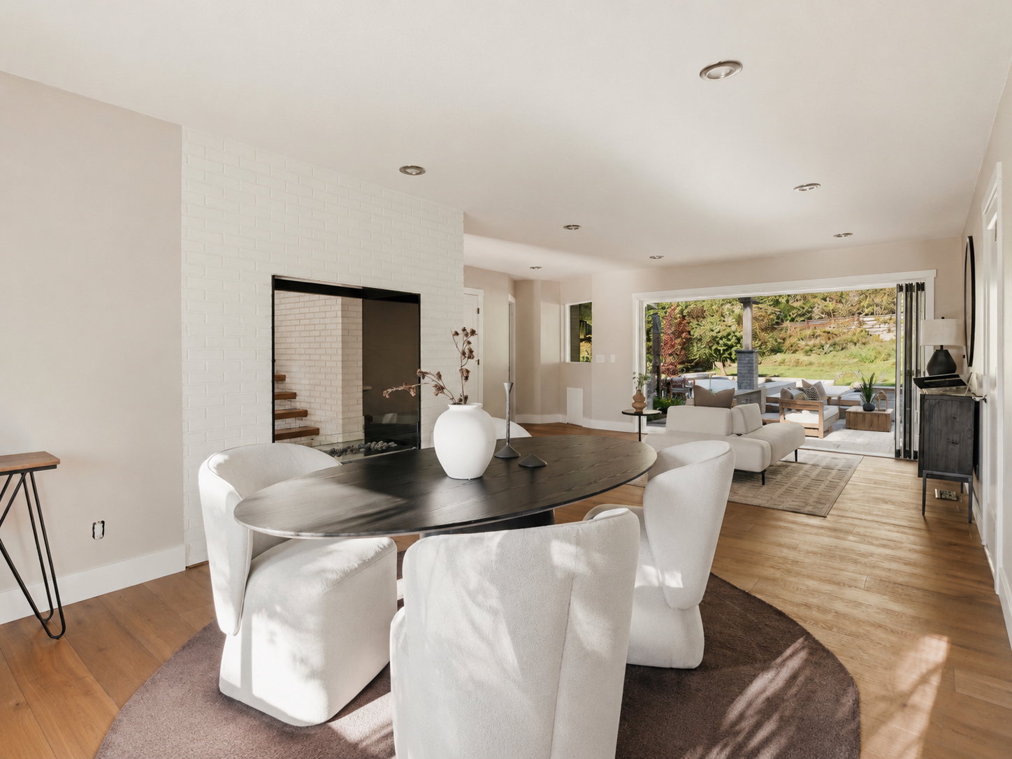 Open-concept interior featuring wood-finish flooring, recessed lighting, and a modern fireplace with a white brick surround