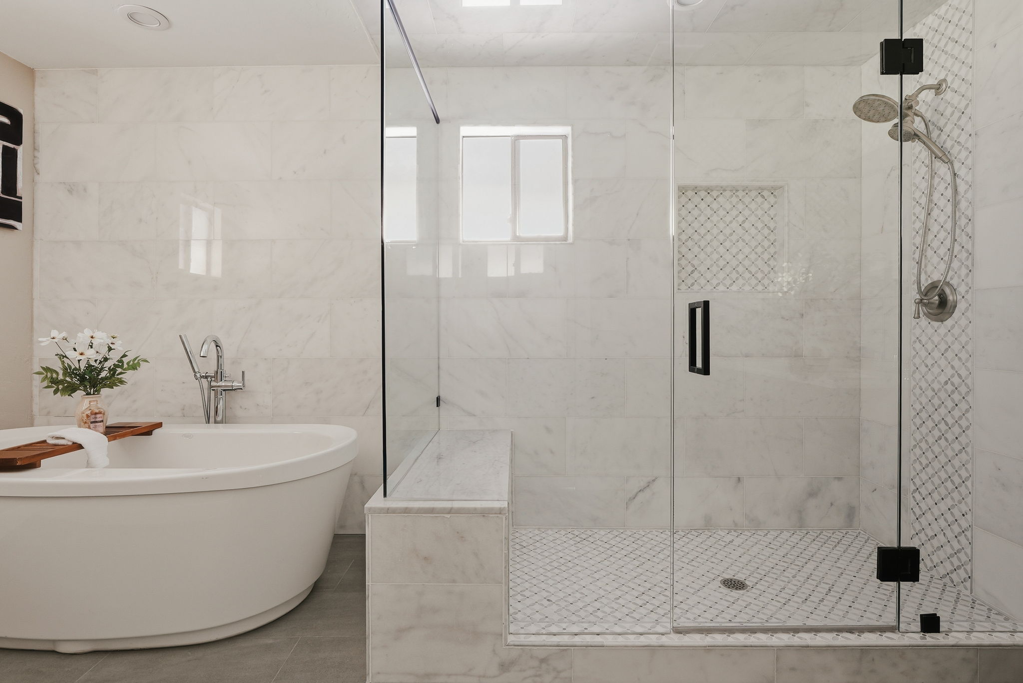 Contemporary bathroom featuring a freestanding soaking tub with floor-mounted faucet, a glass-enclosed shower, marble-look wall tile, and mosaic tile shower floor